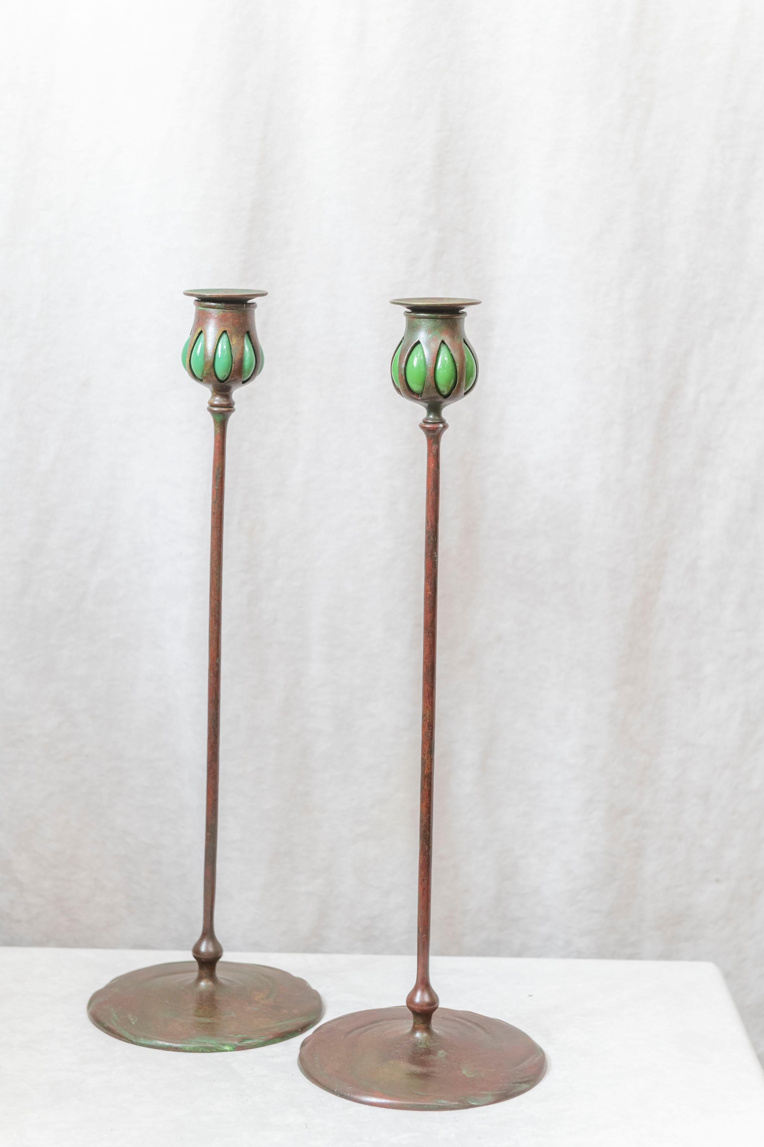 This is the real deal. A fine pair of bronze and glass candlesticks by the most famous maker of lamps, glass and accessories produced in the U.S. These candlesticks are richly patinated and have the bonus of the glass segment. They have all the