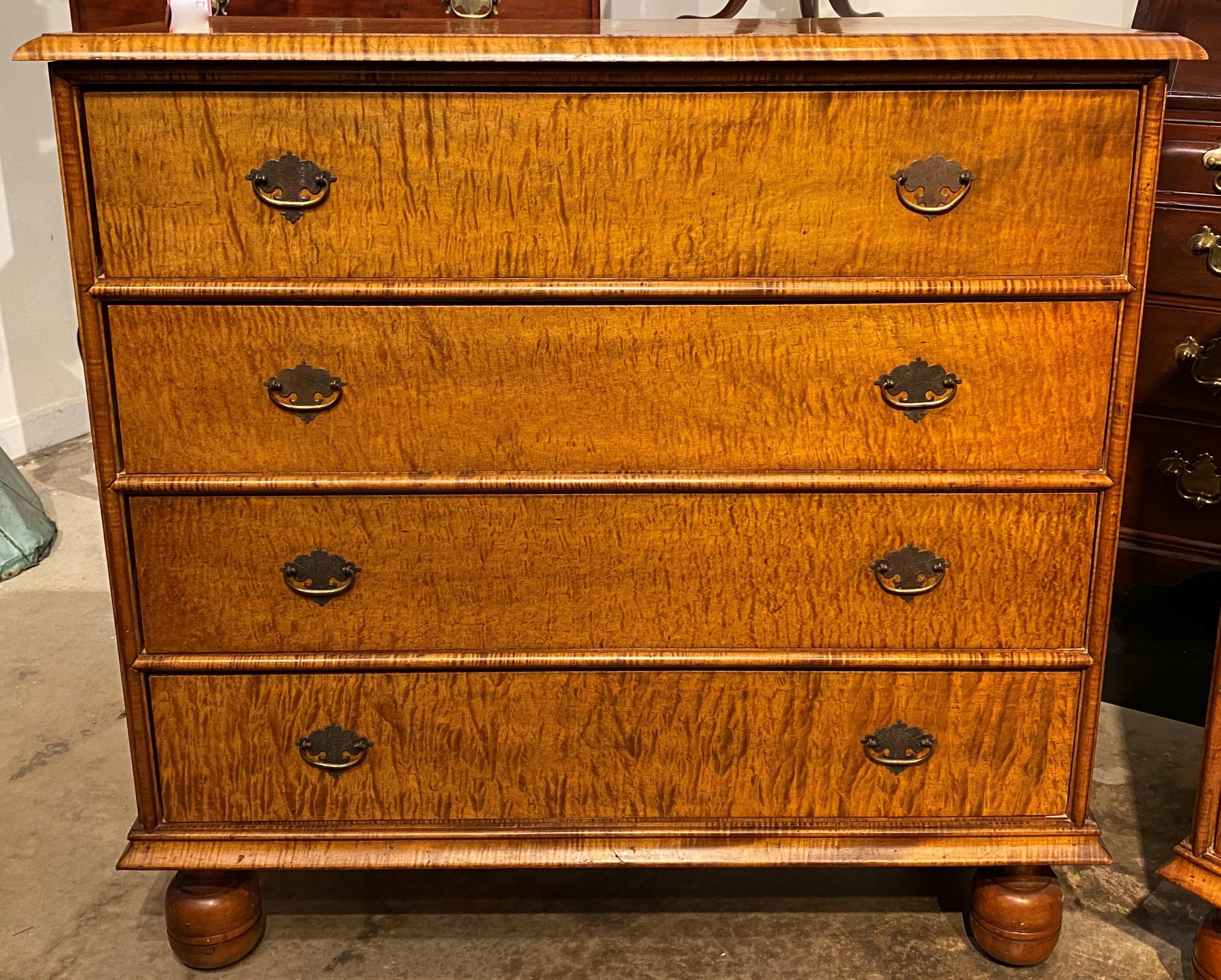 An exceptional pair of tiger maple rectangular chests or dressers in the William & Mary style, with molded edge tops, surmounting a case with four drawers, each with decorative incised brass pulls, each top drawer branded “Wallace Nutting”, and
