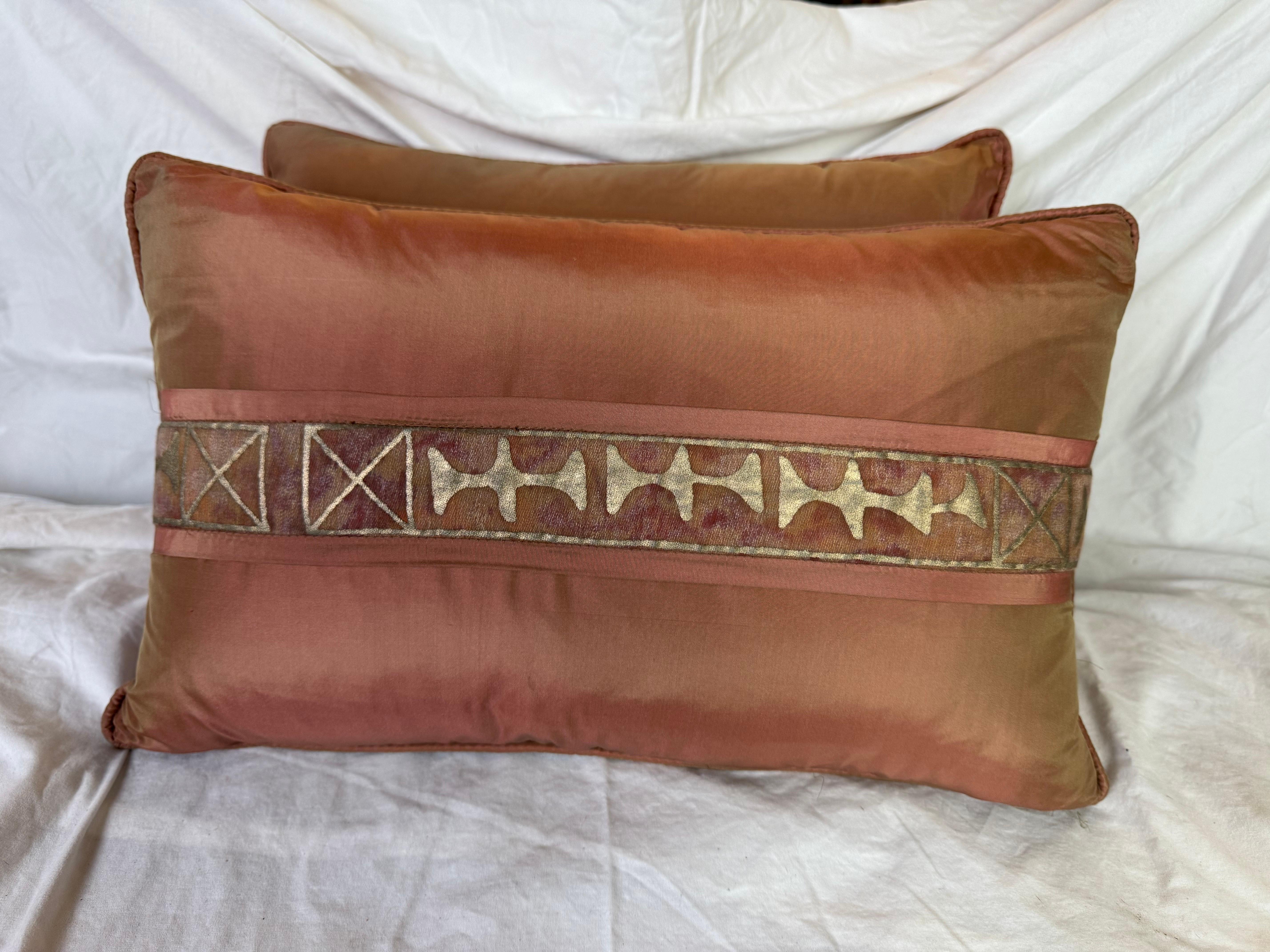 Questi lussuosi cuscini in seta presentano un disegno a righe di Fortuny. Il tessuto di base è una seta ramata ricca, calda e tenue, con una leggera lucentezza che gli conferisce un aspetto elegante e sofisticato.

Una caratteristica fascia