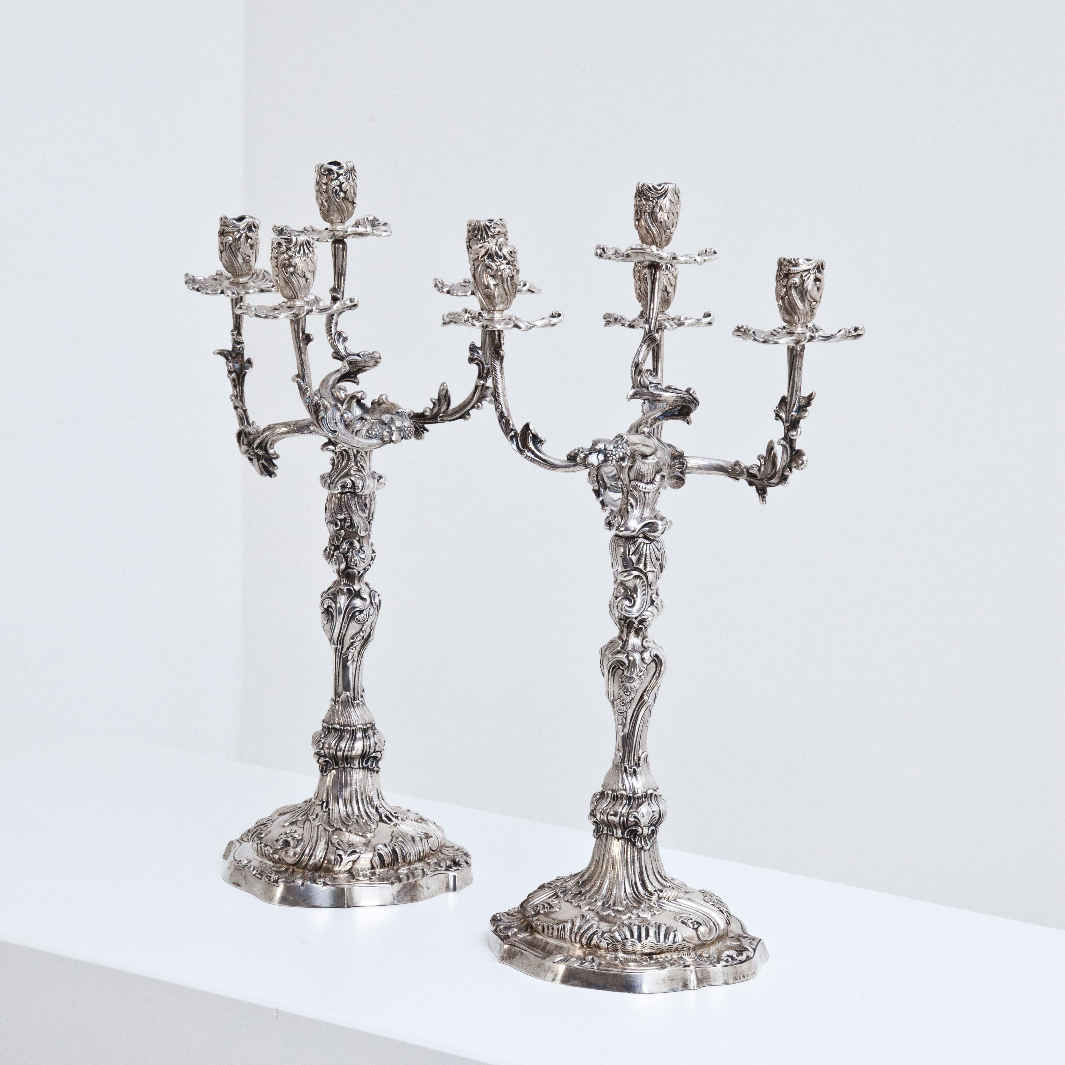Pair of five-armed silver girandoles (2383g and 2485g) in rococo style with opulent rocailles and vine decoration. Stamped Mau, half moon crown, 800 and Dresden.