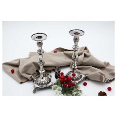 Pair of silver candlesticks with turned stems, floral reliefs, square bases