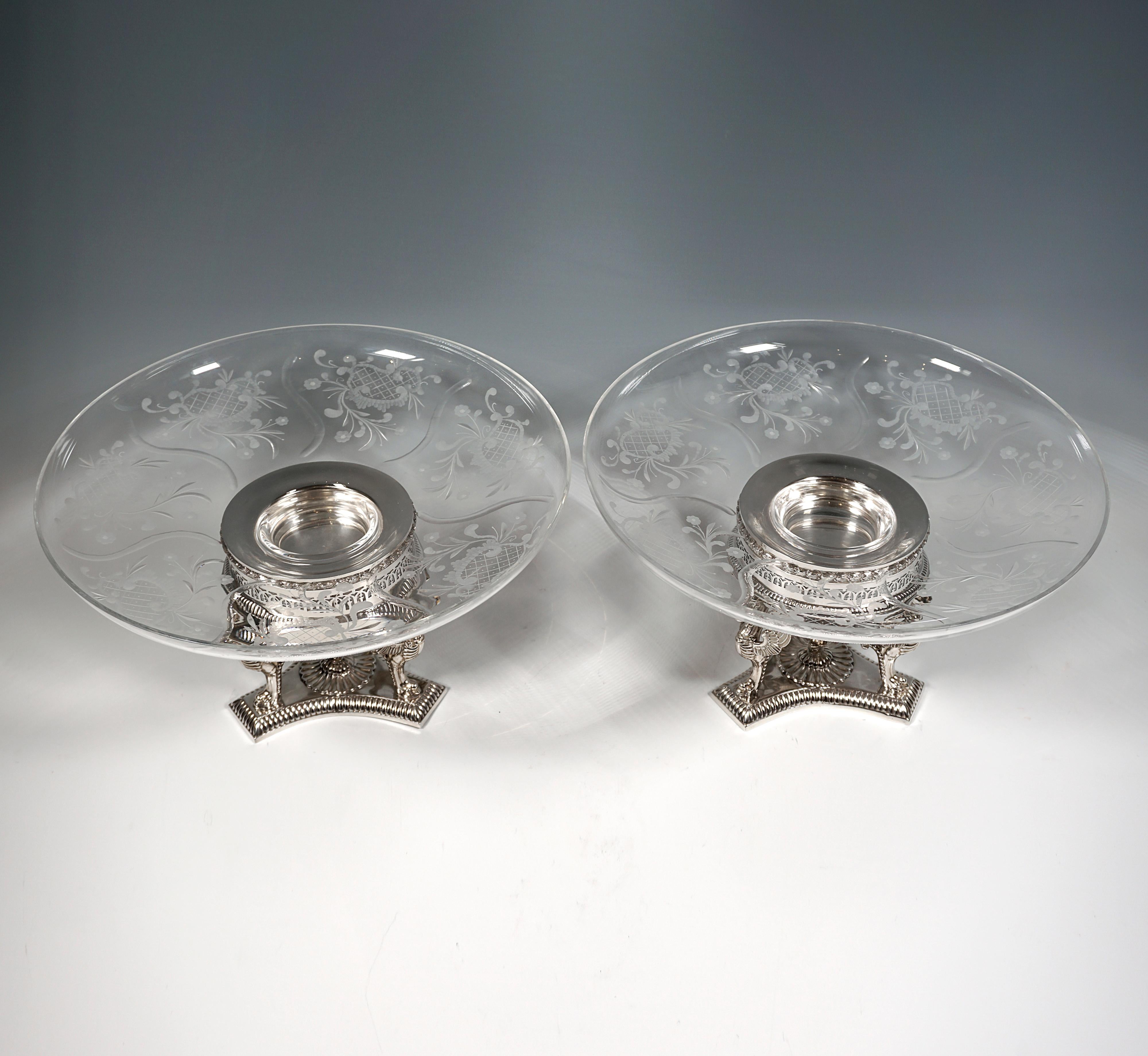 Two elegant silver centerpieces on a three-pass base with delicate embossed decoration and three winged lion figures supporting the richly ornamented and pierced insert for the projecting, artfully cut glass bowls.

Total dimensions piece:
height:  