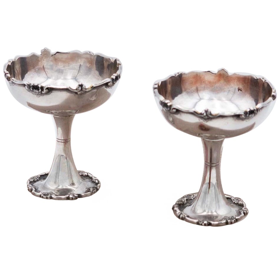 Pair of silver cups with rims and bases with raised friezes