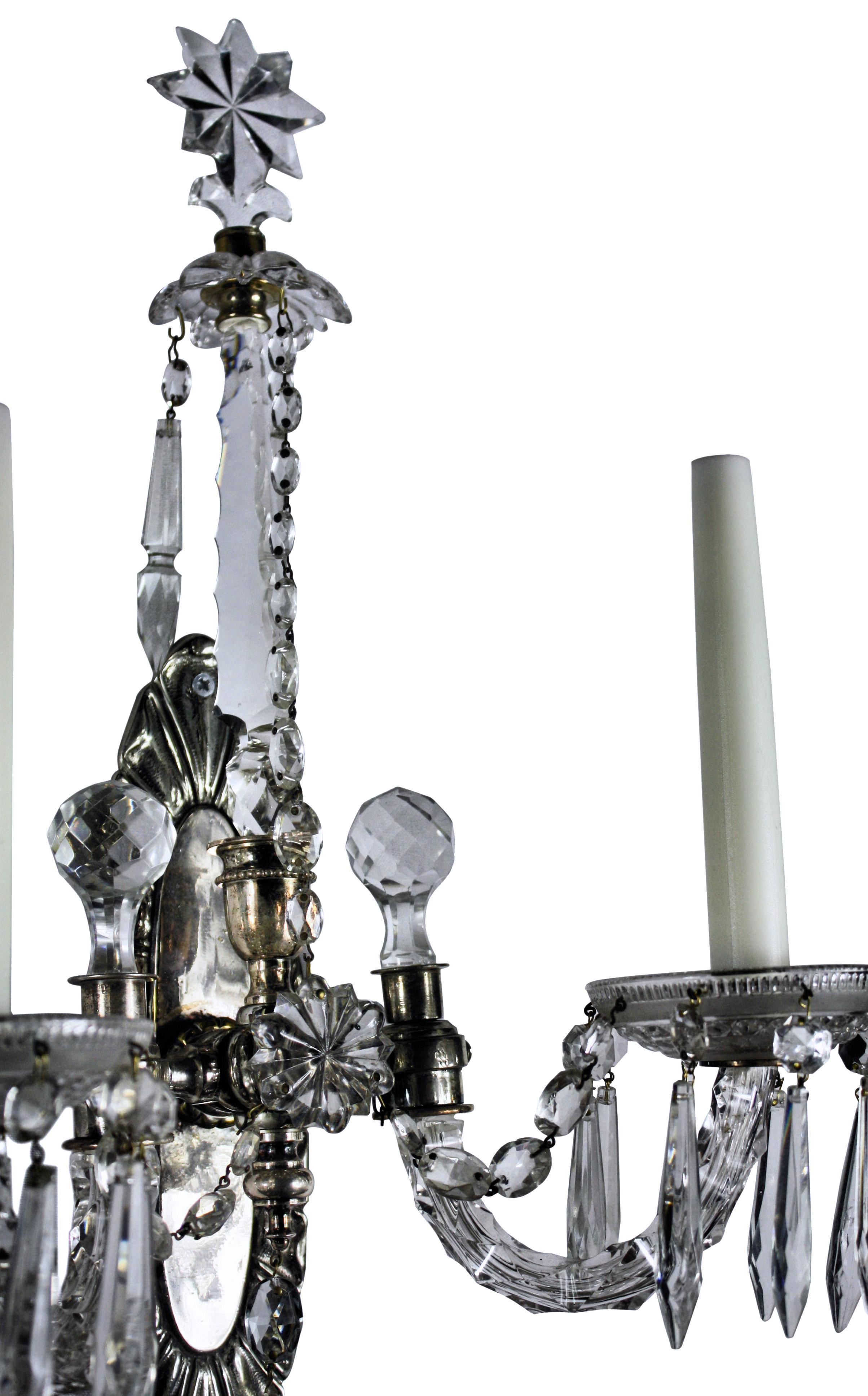 Pareja de apliques ingleses de doble rama, de plata y cristal tallado, con agujas terminadas en estrellas con guirnaldas y colgantes.