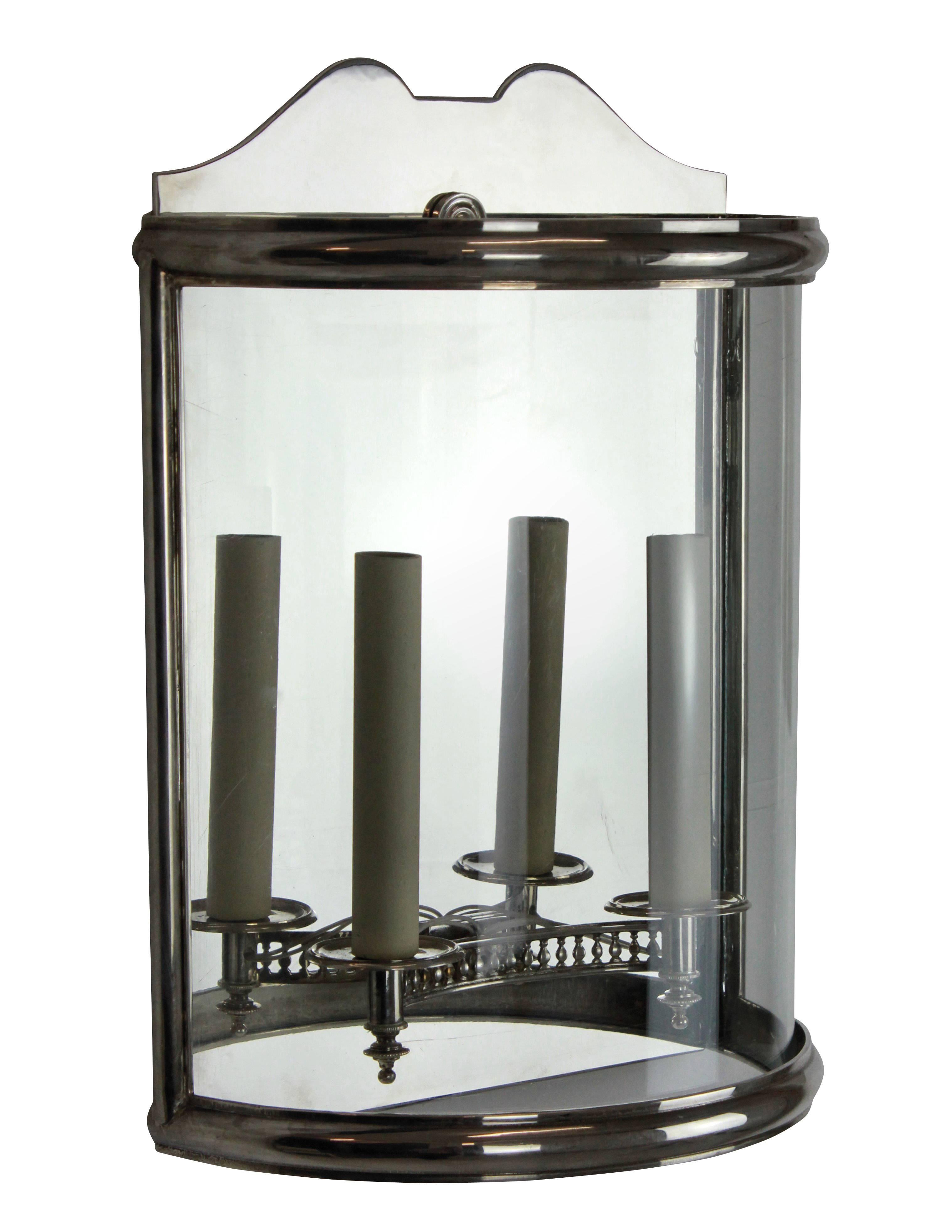 A pair of good quality English demilune wall lanterns in silver plated brass. Of simple Georgian design with a single curved panel of glass.

 