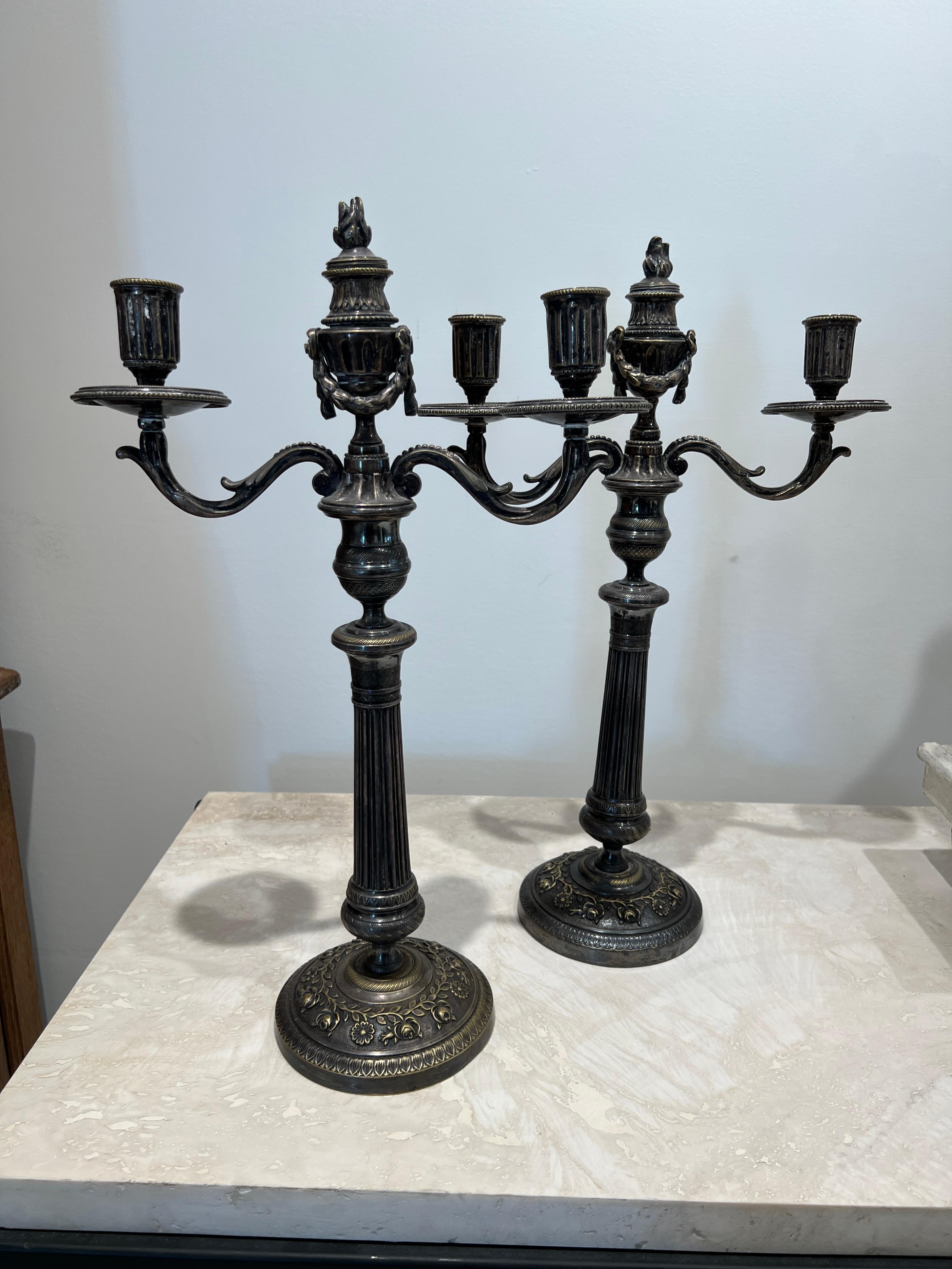 A matching pair of silver plated double candlesticks with an articulating decorative swag in the middle. Lovely lines, details and proportions for adding lighted tapers to your tablescape.