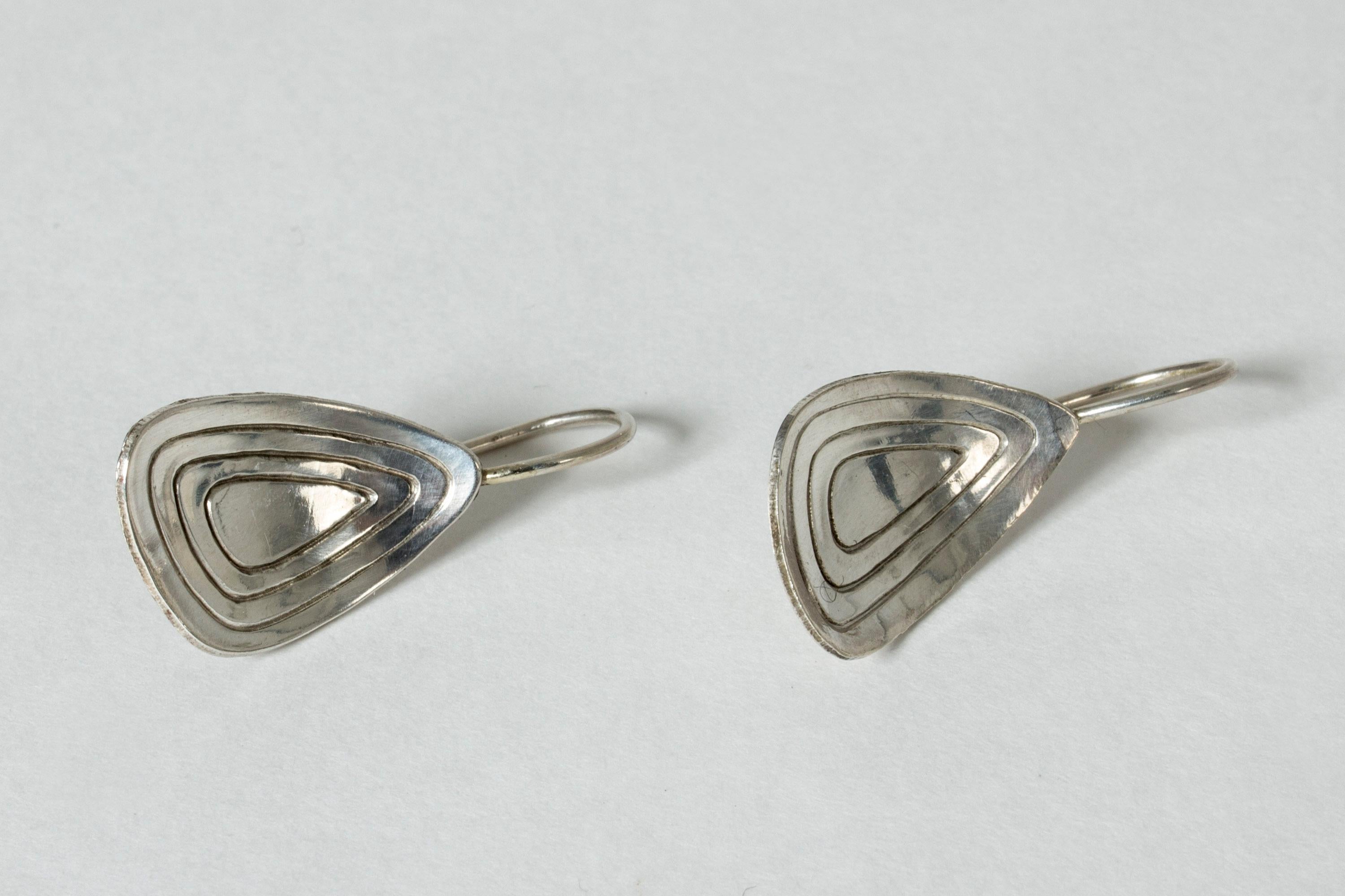 Cool silver earrings from Alton, with a convex triangular shape. Stylized shell like pattern in the middle. The original screws have been replaced with hooks.