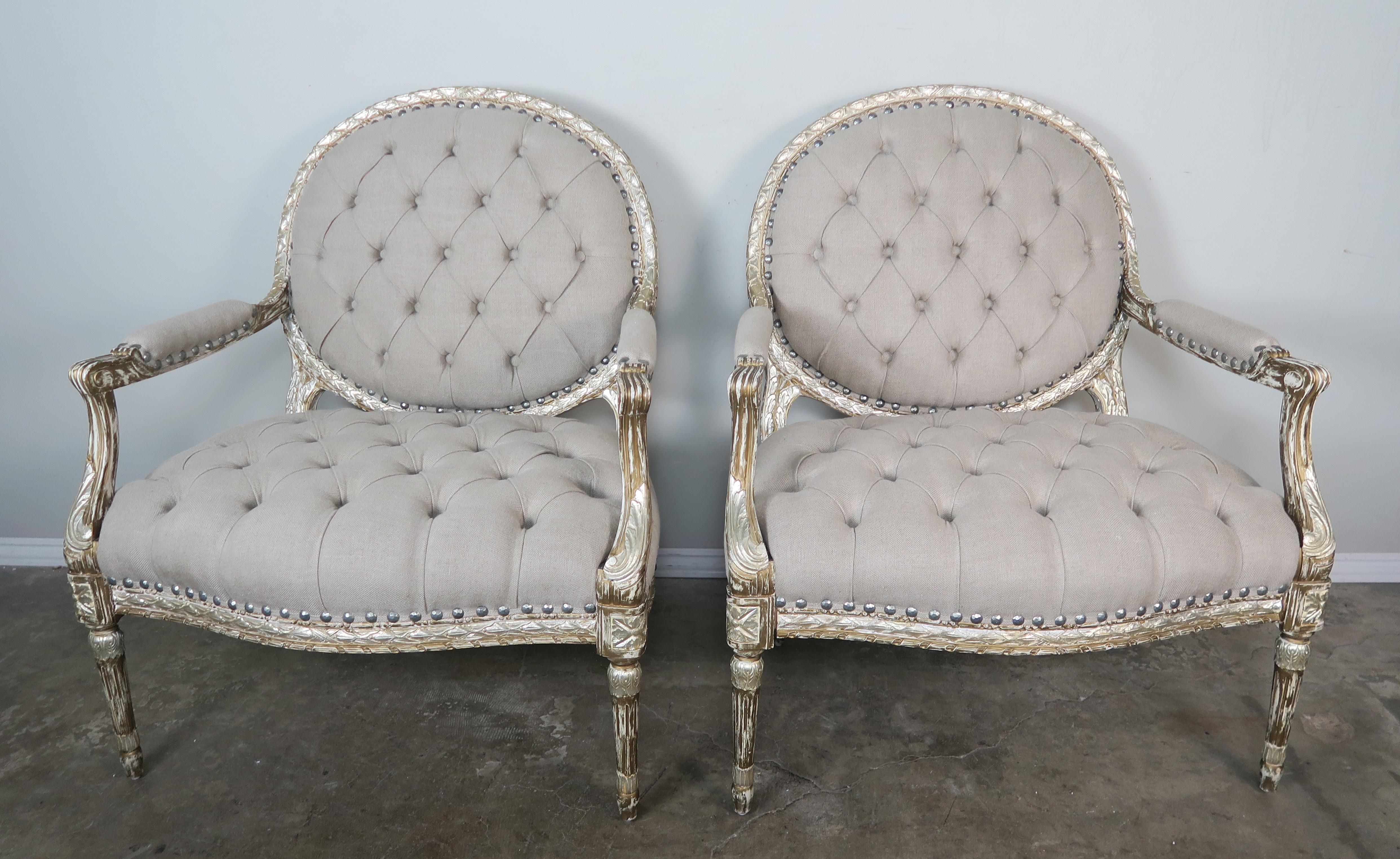 Pair of silver gilt carved neoclassical style armchairs newly upholstered in a tufted washed oatmeal coloration. When you.
