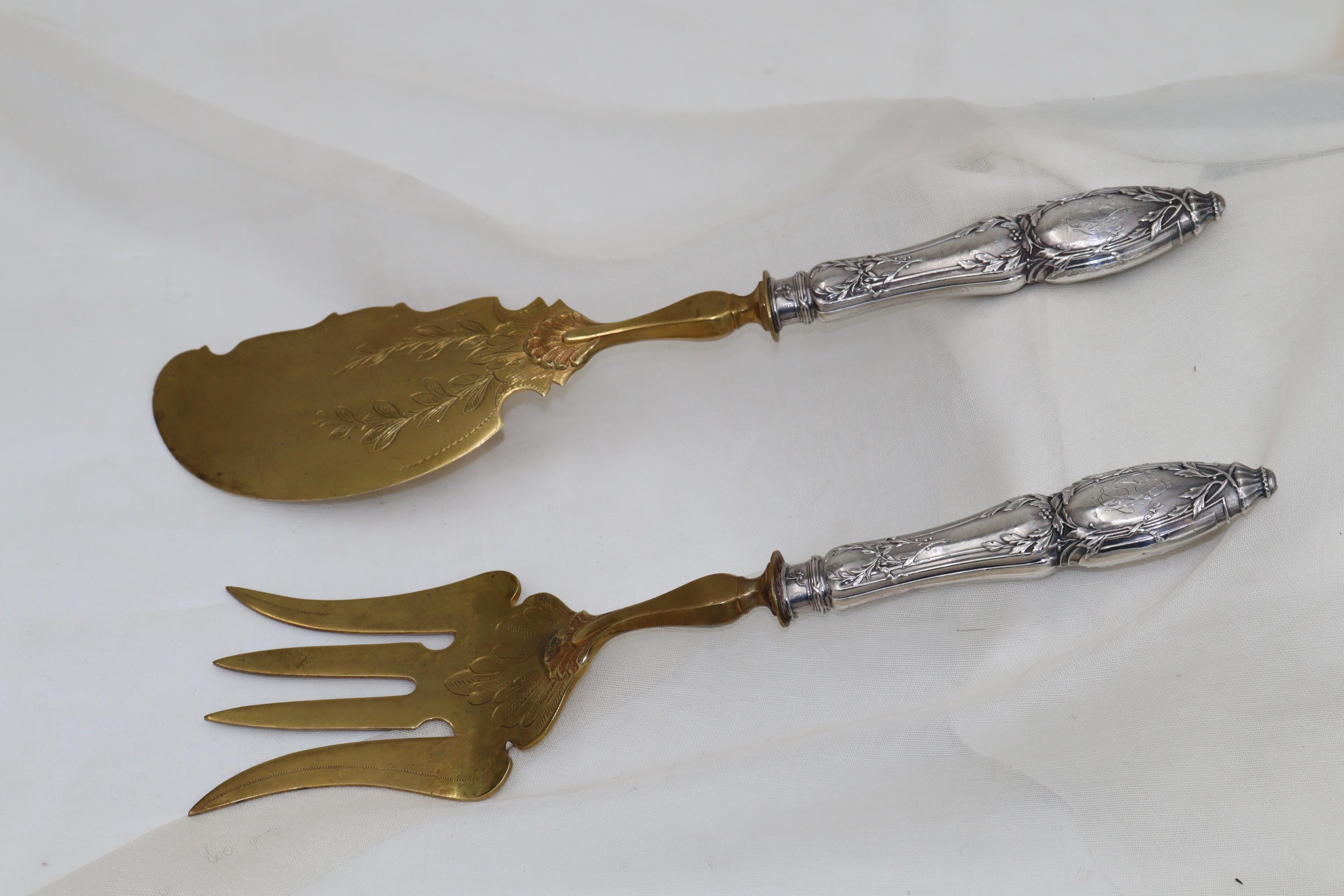 I manici d'argento di questi pesciolini in argento dorato di buona qualità sono decorati con ghirlande neoclassiche e le lame sono state incise prima della doratura. Ciascuna delle maniglie è incisa con un monogramma molto decorato. Il coltello da