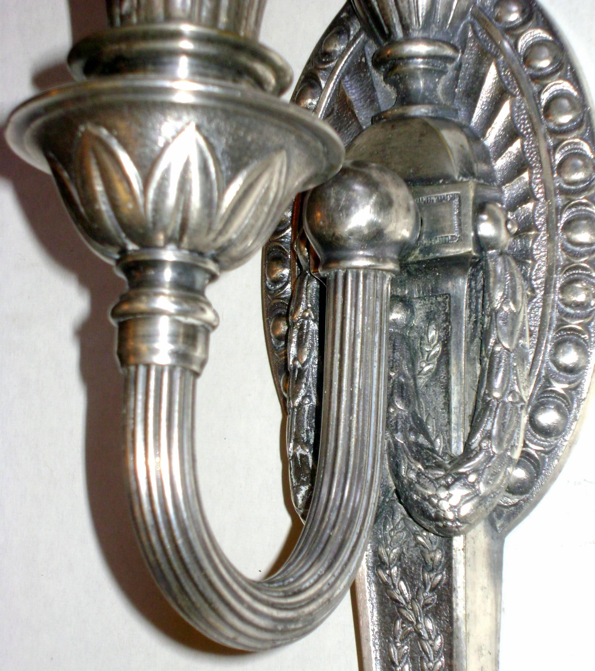 Coppia di applique a una luce in stile neoclassico inglese degli anni '20 con finitura argentata.

Misure:
Altezza 14,75
Larghezza 3,75
Profondità 5