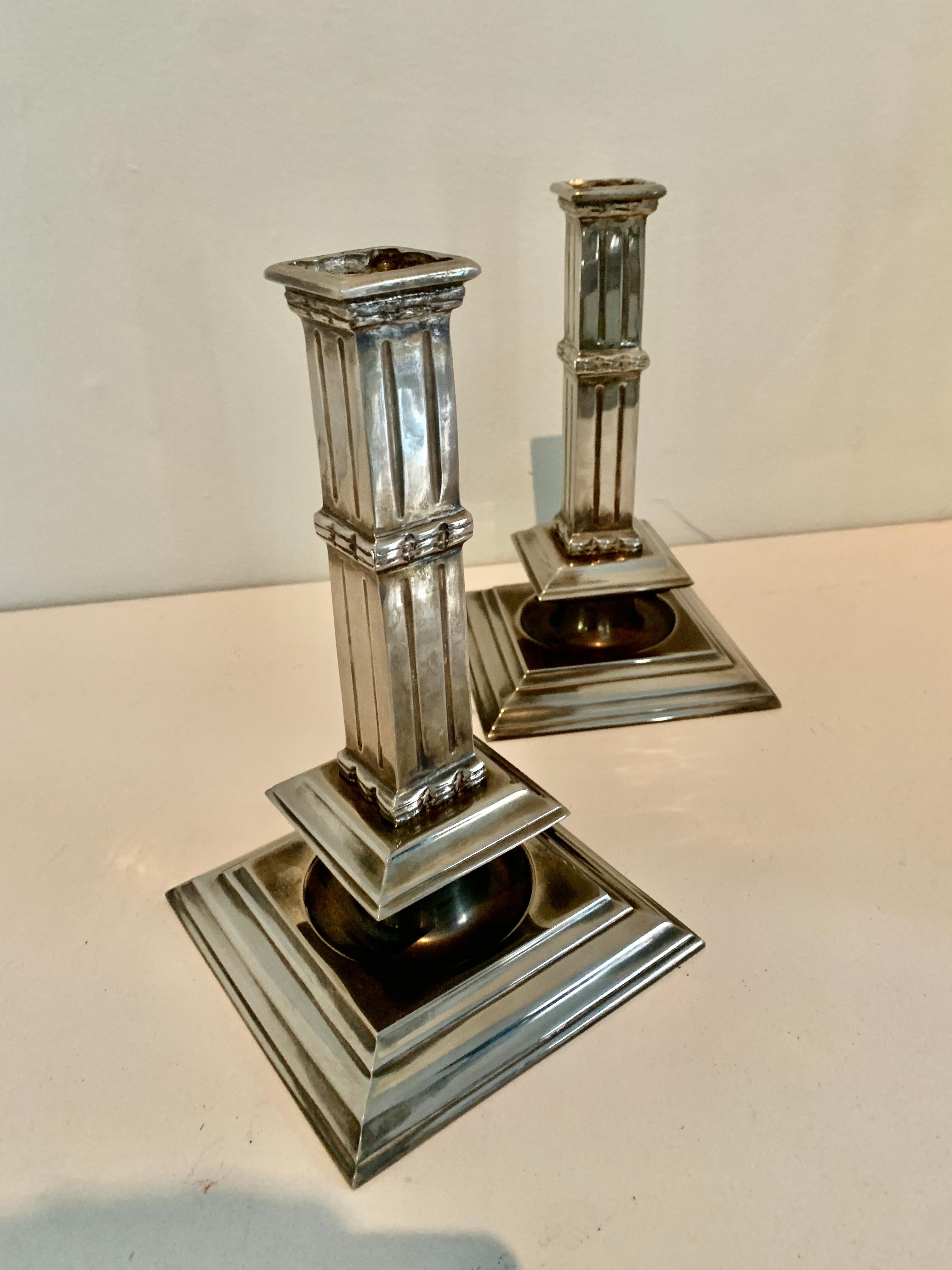 A wonderfully architectural Pair of silver plate candlesticks - the pair are reminiscent of columns and are a compliment to any dining table, mantle or console. The finish is a polished silver with great depth. Exquisite, simple and