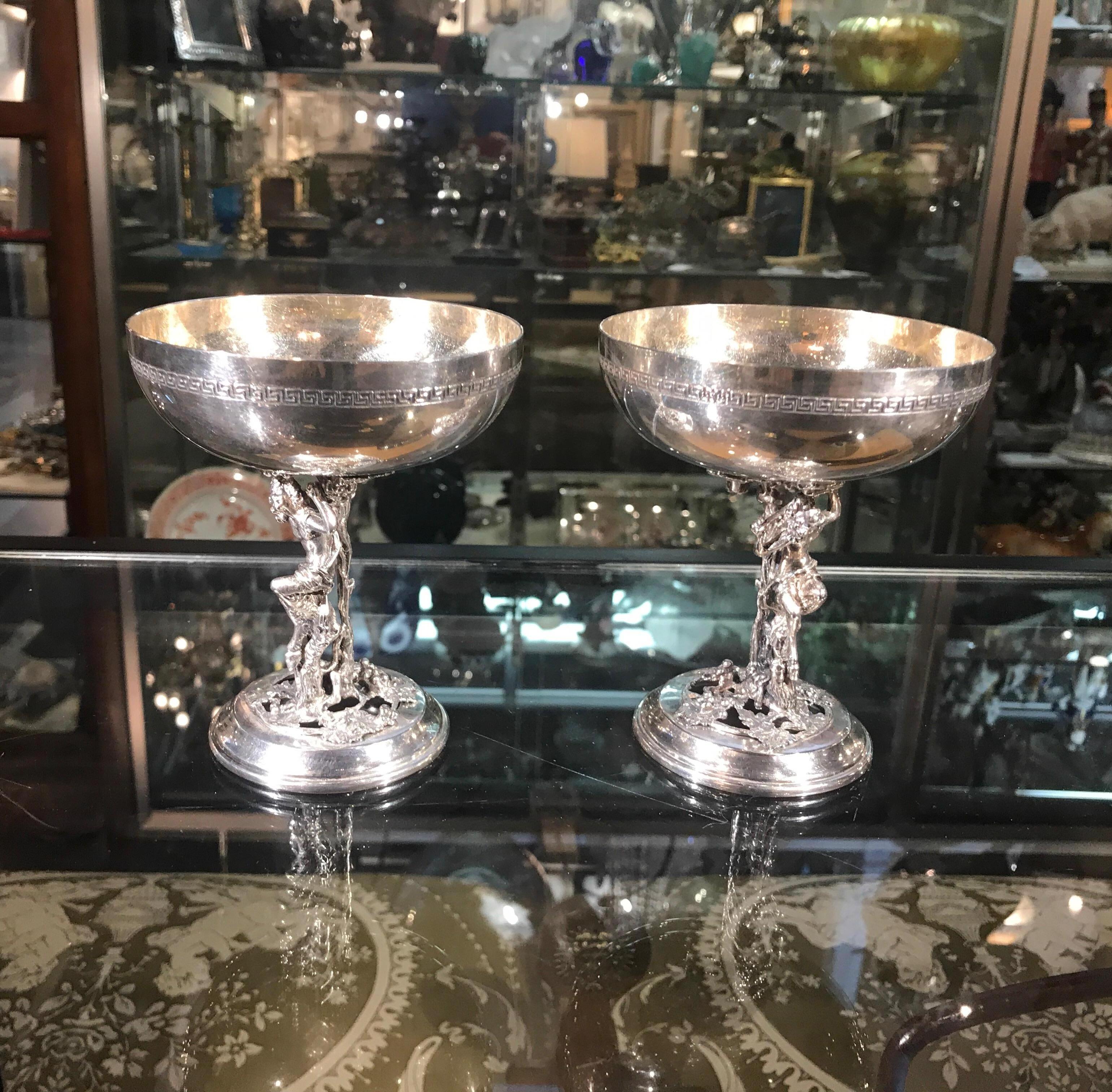 A pair of Bacchanalian motif champagne coups made in Spain. The bowl tops with Greek key pattern on the outside with a cast figure of Bacchus at the stem.