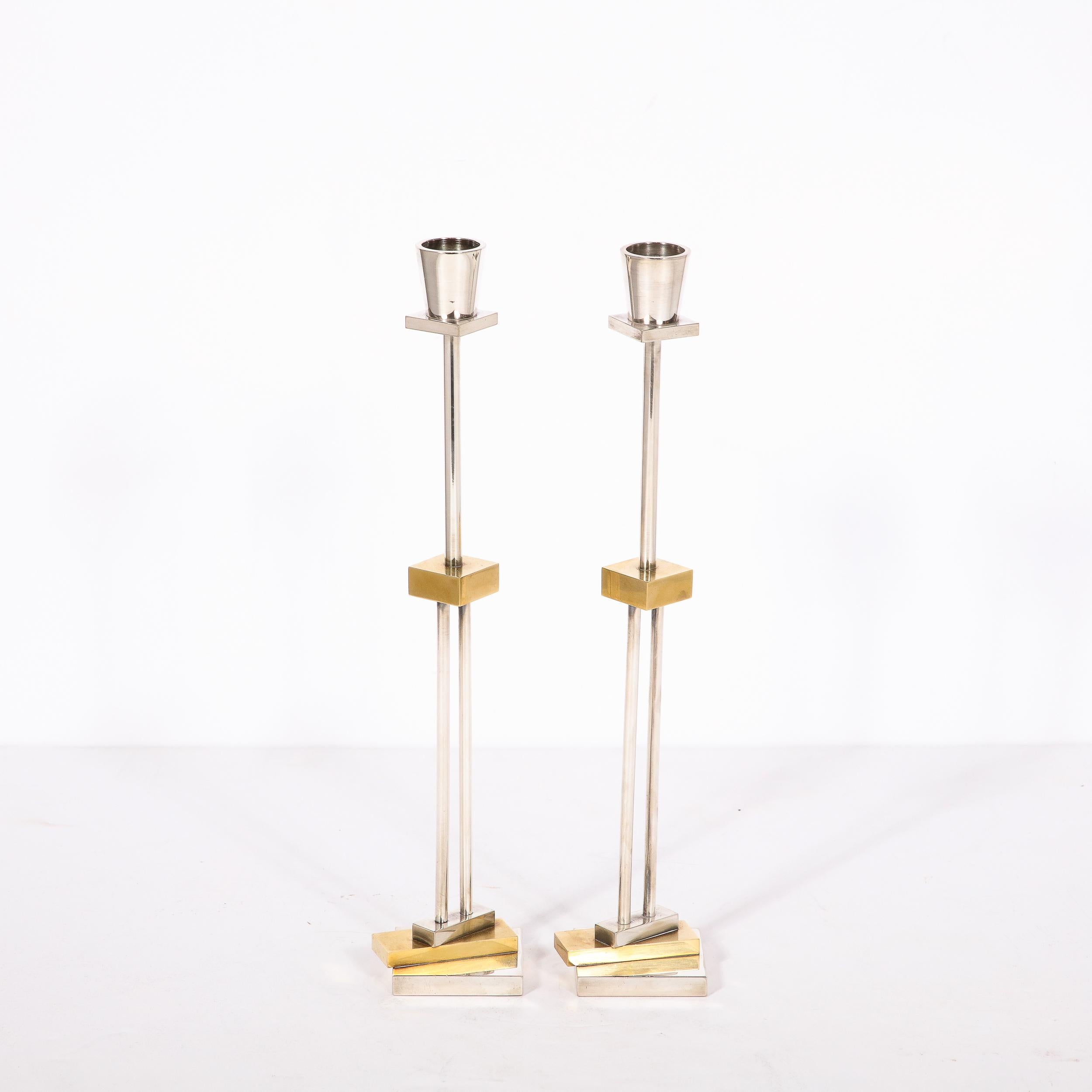 This stunning pair of post modernist candlesticks were realized by the iconoclastic and inimitable Ettore Sottsass for Swid Powell. These pieces feature a volumetric square silverplated base stacked with a brass rectangular panel at a biased angle