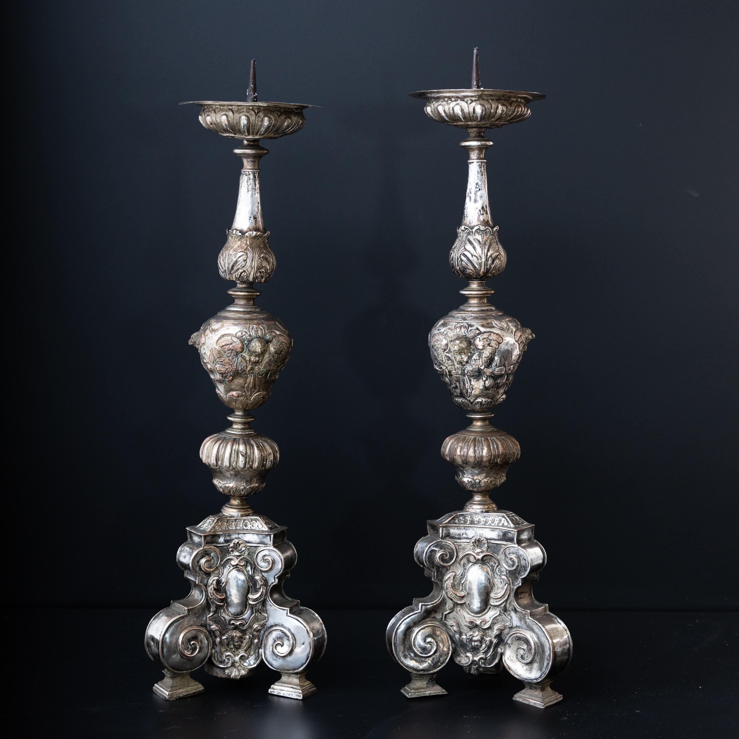 Pair of silver-plated altar candlesticks with putti decoration and elaborately balustraded shafts. The diameter of the drip tray is 10cm.