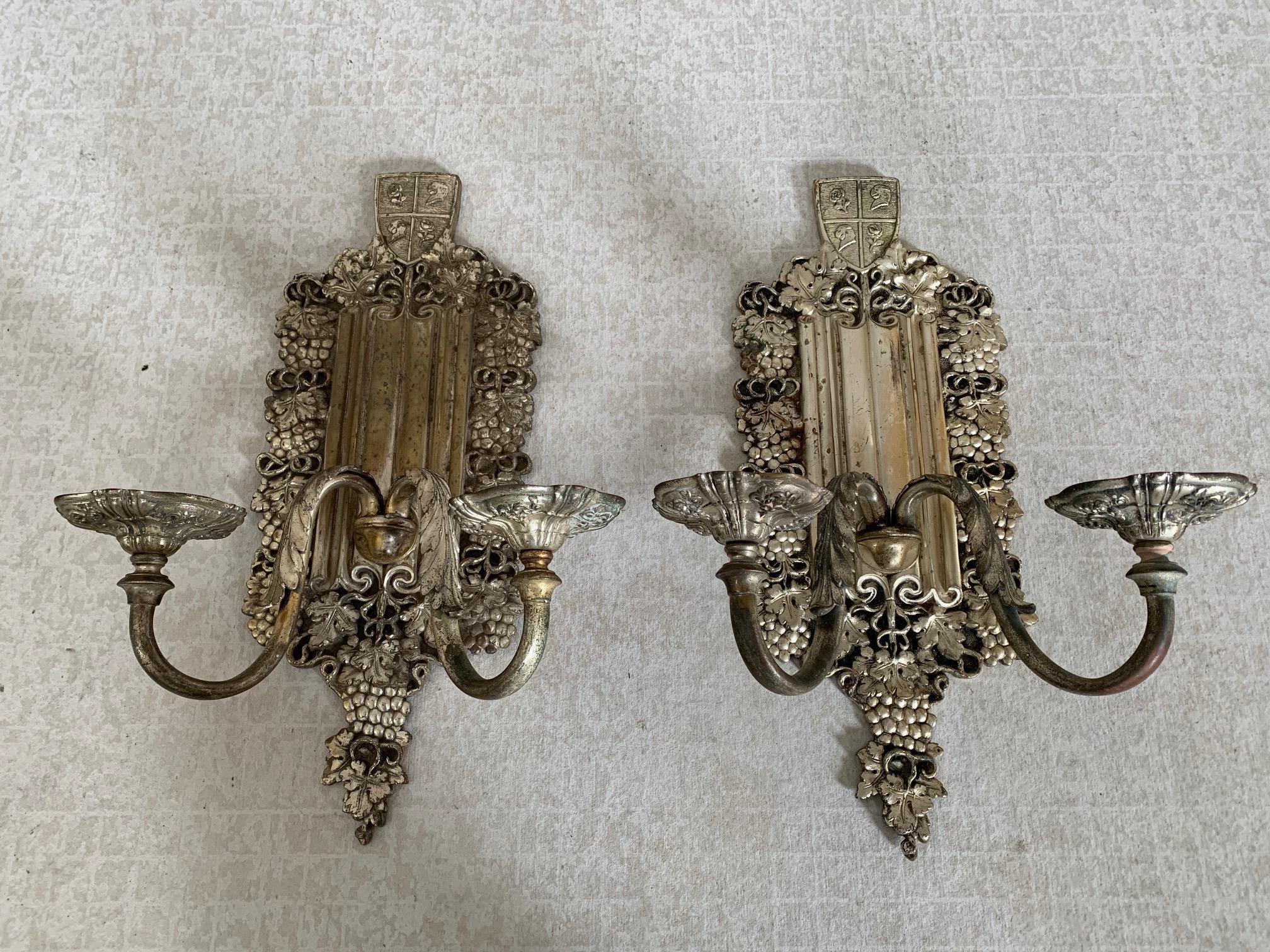 Bronze argenté, appliques à deux bras avec bordure en raisin, plaque arrière en lin et bouclier héraldique en forme de griffon et de rose.
Attribué à E. F.Caldwell, New York, vers 1925.
Le placage est usé par endroits mais largement intact.