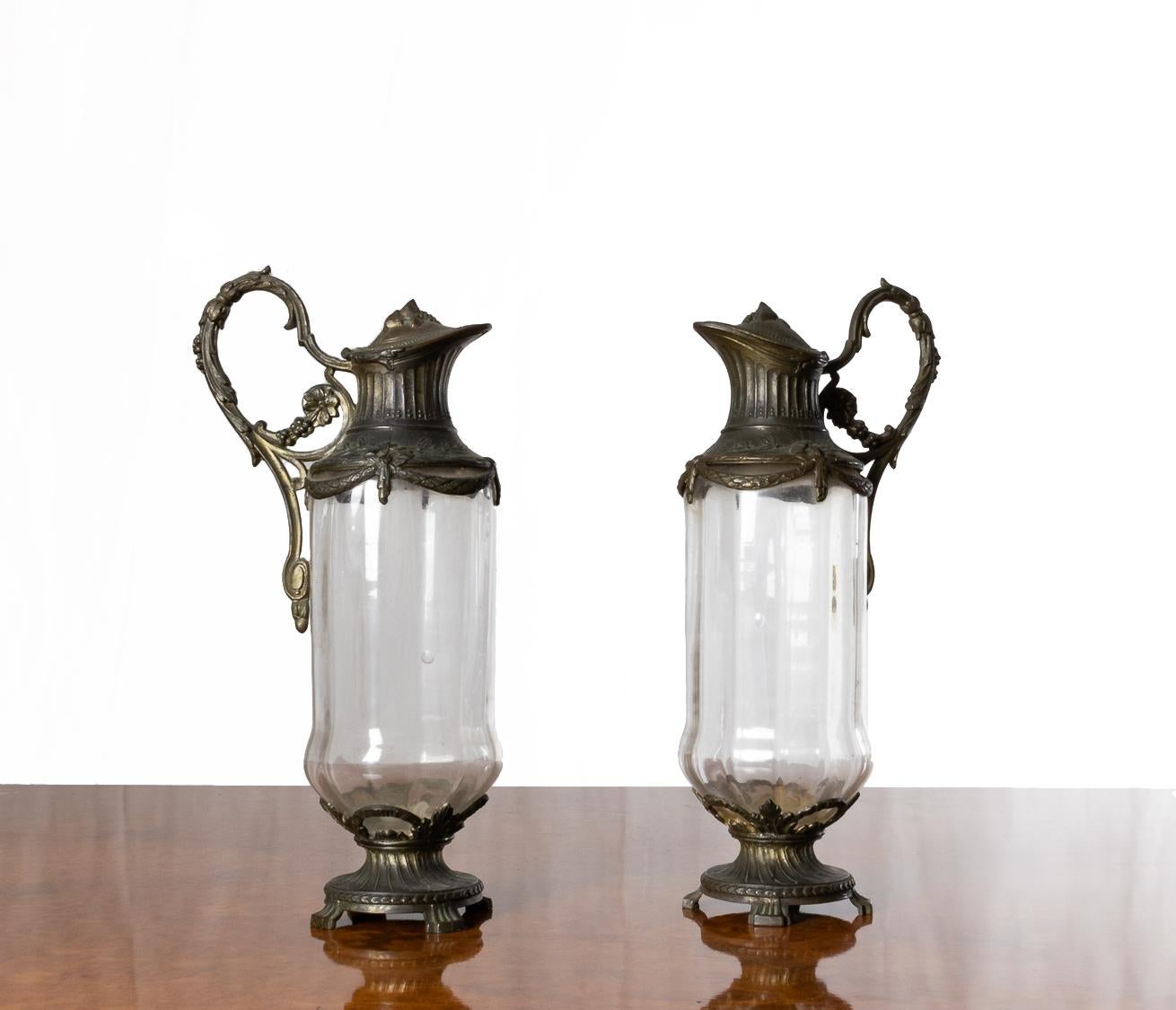 Una bella coppia di caraffe da Claret in stile Impero, placcate in argento e decorate con viti e uva, con vetro trasparente e piedini placcati. 
Un notevole esempio di Eleganza all'alba del XX secolo.