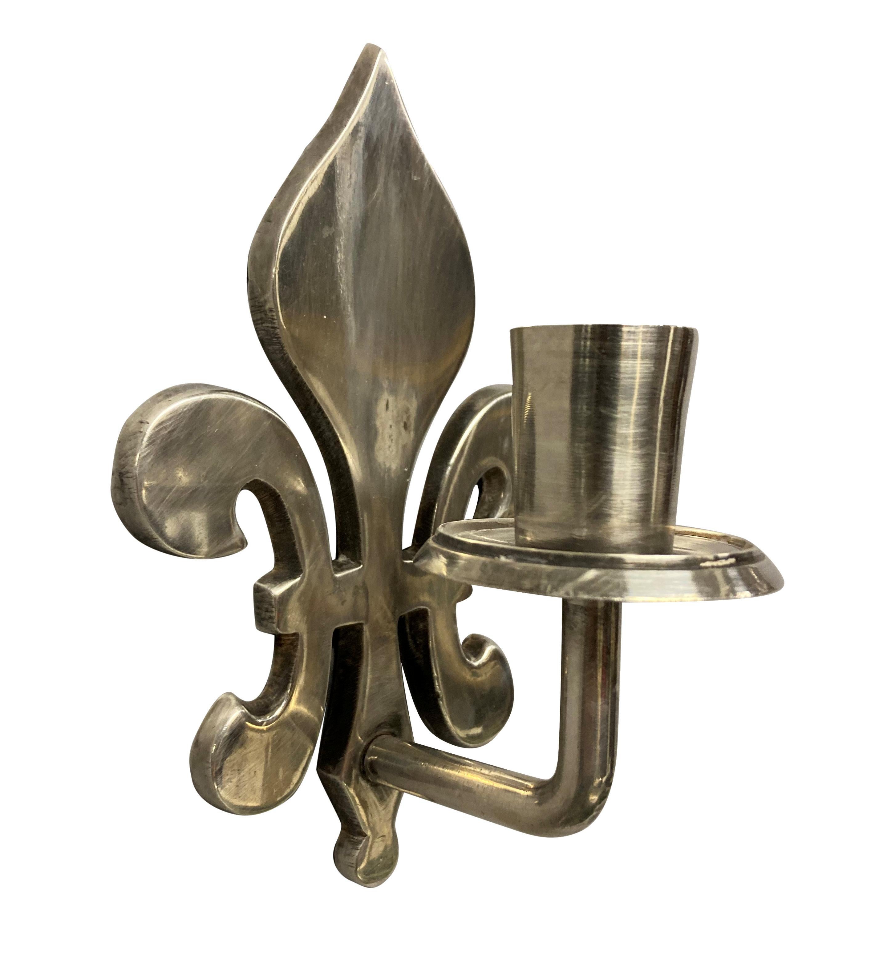A pair of French silver-plated fleur de lys single arm candle sconces.