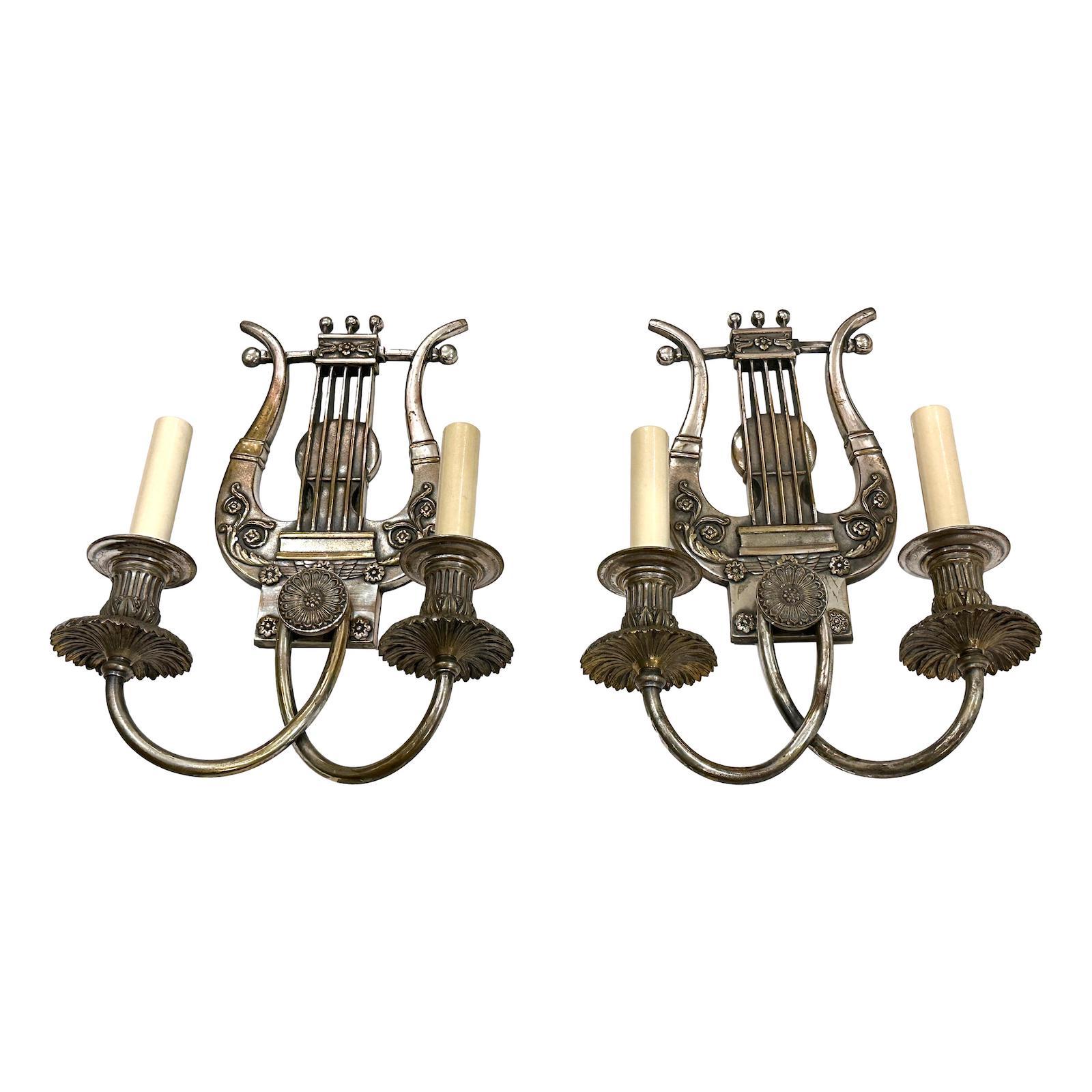 Pair of circa 1940's English silver plated neoclassic style two-arm lyre sconces.

Measurements:
Height: 13.5