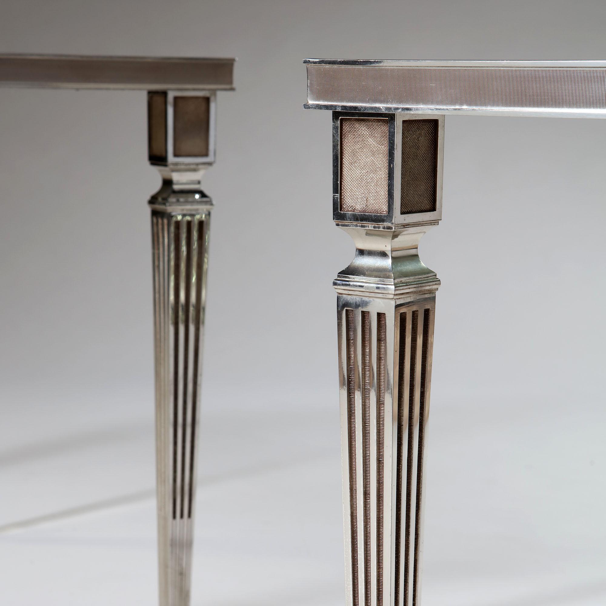 A fine pair of square silver plated occasional tables, retaining the original smoked glass tops (with minor losses to the corners), all supported on fluted legs in the Neoclassical style with toupie feet.

Jean-Henri Jansen, originally from Denmark,
