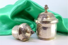 Pair of silver pots with beaded edges, floral reliefs, and flower knobs
