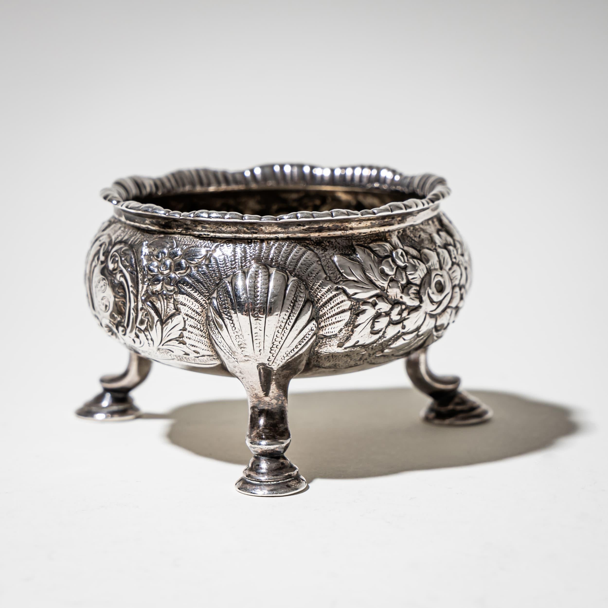 Paire de salières en argent reposant sur trois pieds cabriole, à décor repoussé de motifs de coquilles et de rocailles et à bord festonné. Un bel exemple d'orfèvrerie rococo anglaise. Poinçon sur la face inférieure ; lettre de date partiellement