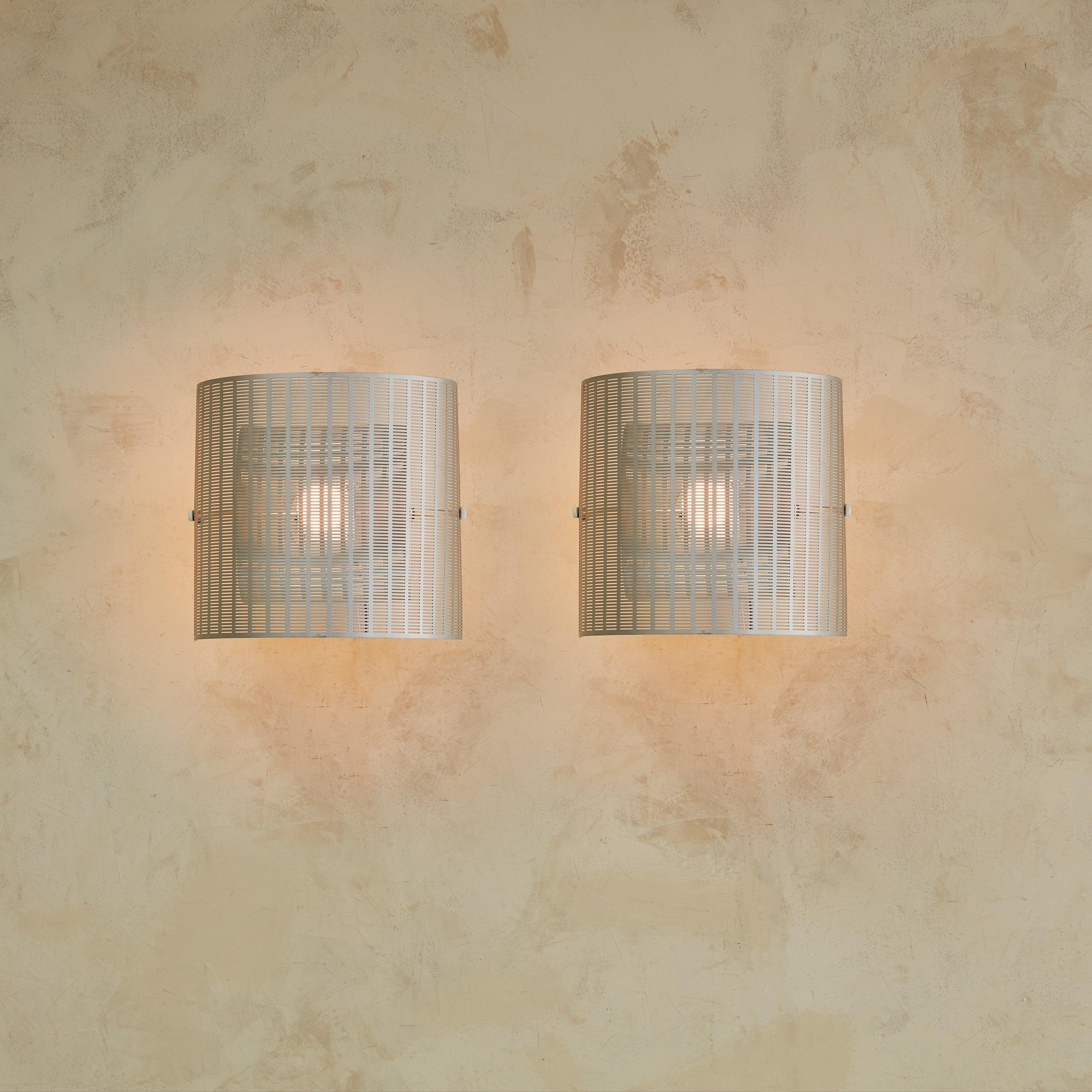 A rare pair of ‘Shogun’ wall sconces designed by Swiss Architect Mario Botta for Artemide in 1986. These iconic sconces feature adjustable perforated silver enameled metal shades, which provide beautiful ambient lighting and mesmerizing shadow