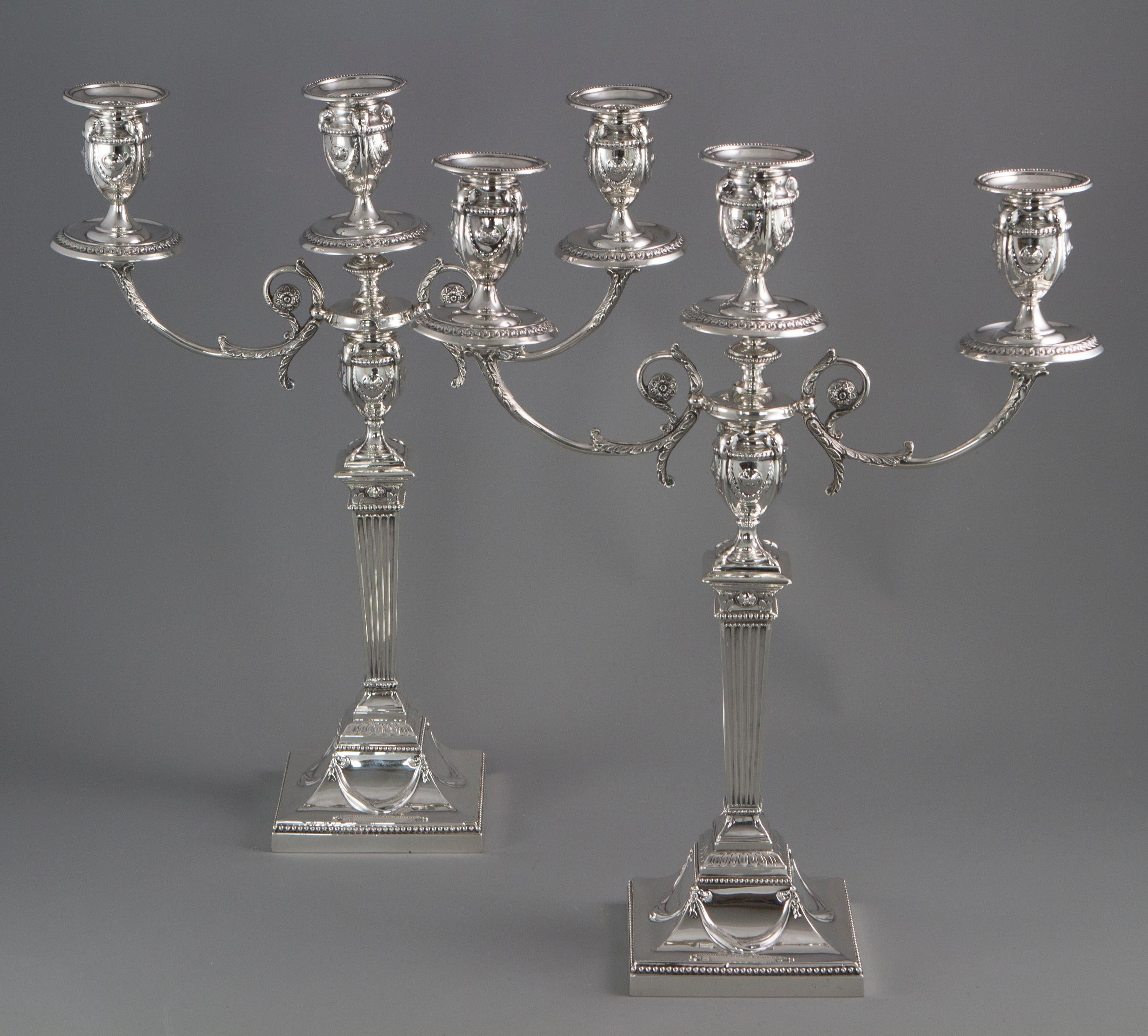 A very good quality pair of Neo Classical style Victorian silver candelabra. The sticks with a square beaded base with swag decoration. A tapered reeded column leading to a garlanded urn sconce on a flower and beaded capital. The scrolling arms with