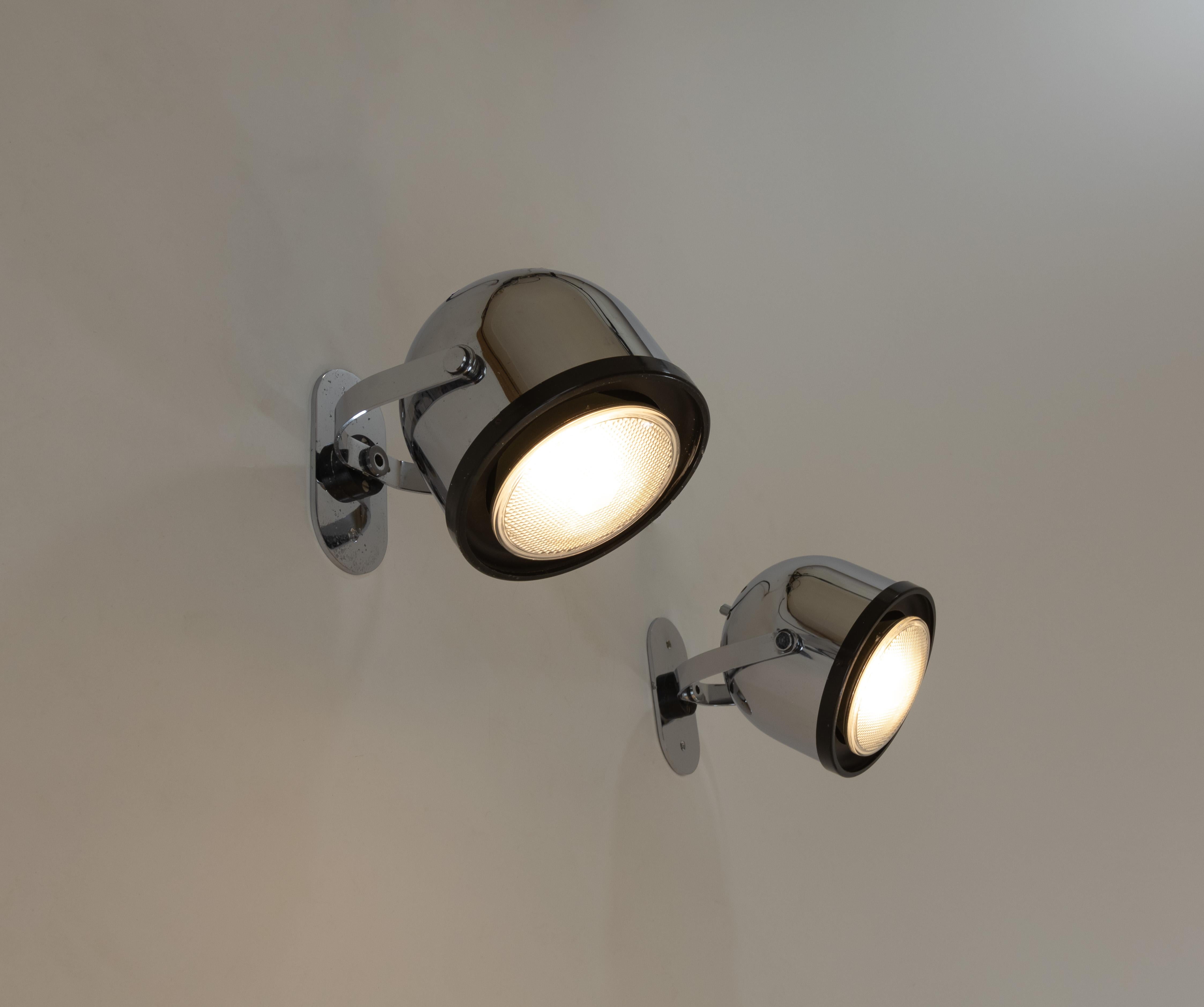 Coppia di spot girevoli in metallo cromato disegnati da Gae Aulenti e Livio Castiglioni per Stilnovo negli anni '70. Gli spot possono essere utilizzati anche come lampade da soffitto.

Gli spot o i proiettori sono dotati di un doppio movimento di