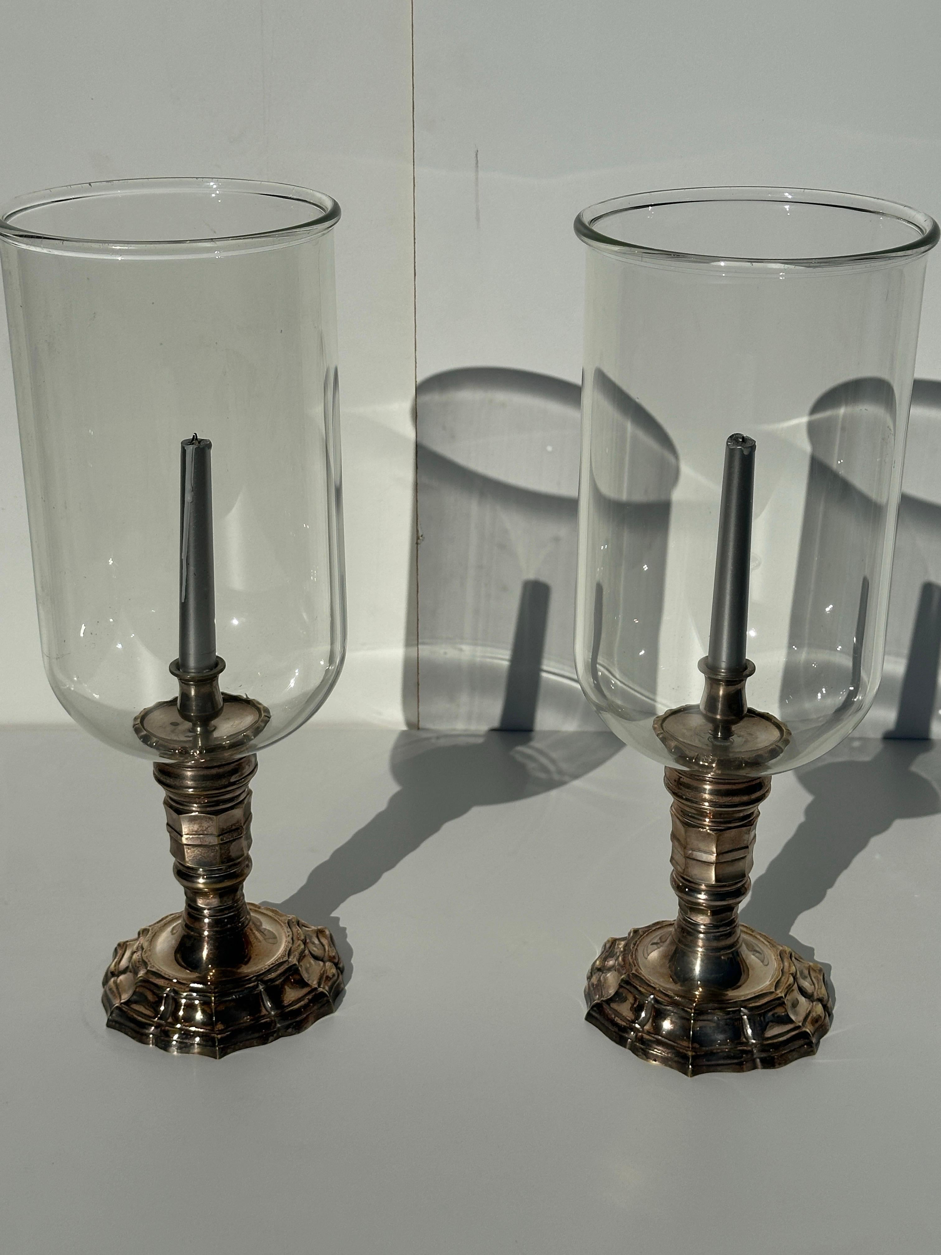 Pair of silvered brass candle hurricanes in the style of Chapman with intricate scalloped design base.