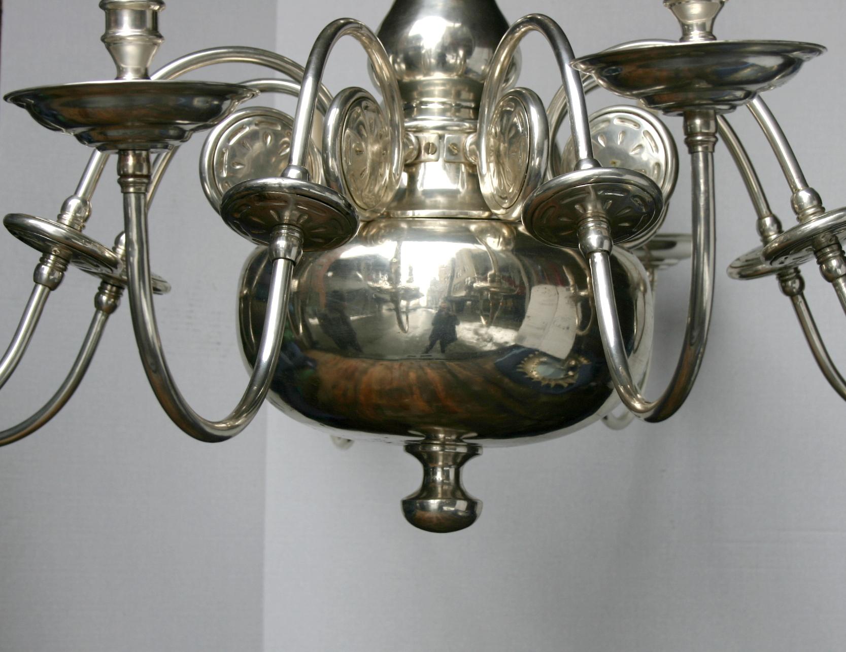 A pair of circa 1930's silver-plated eight-arm Dutch chandeliers with large central body, scrolling arms and oversized cups. Sold individually.

Measurements:
Diameter: 46.5