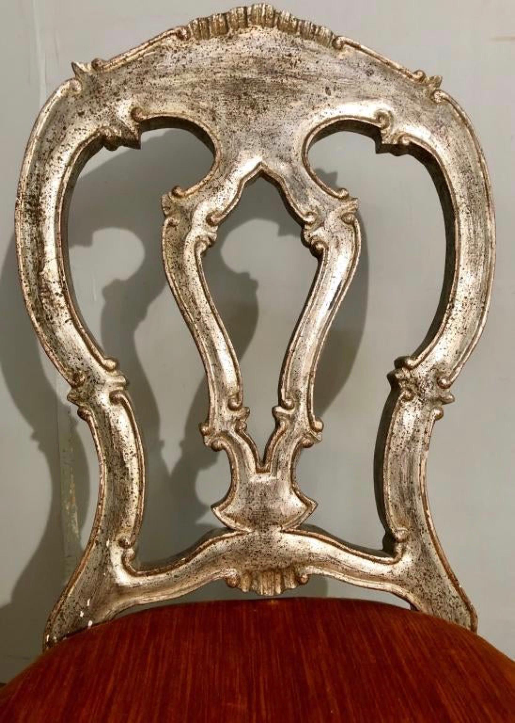 Pair of silver paint decorated Italian Rococo dining side chairs. Chairs are wonderfully carved in the Grotto fashion with arched backs supported by gently scalloped apron and cabriole legs. Upholstered seats shows wear. Great as extra dining room