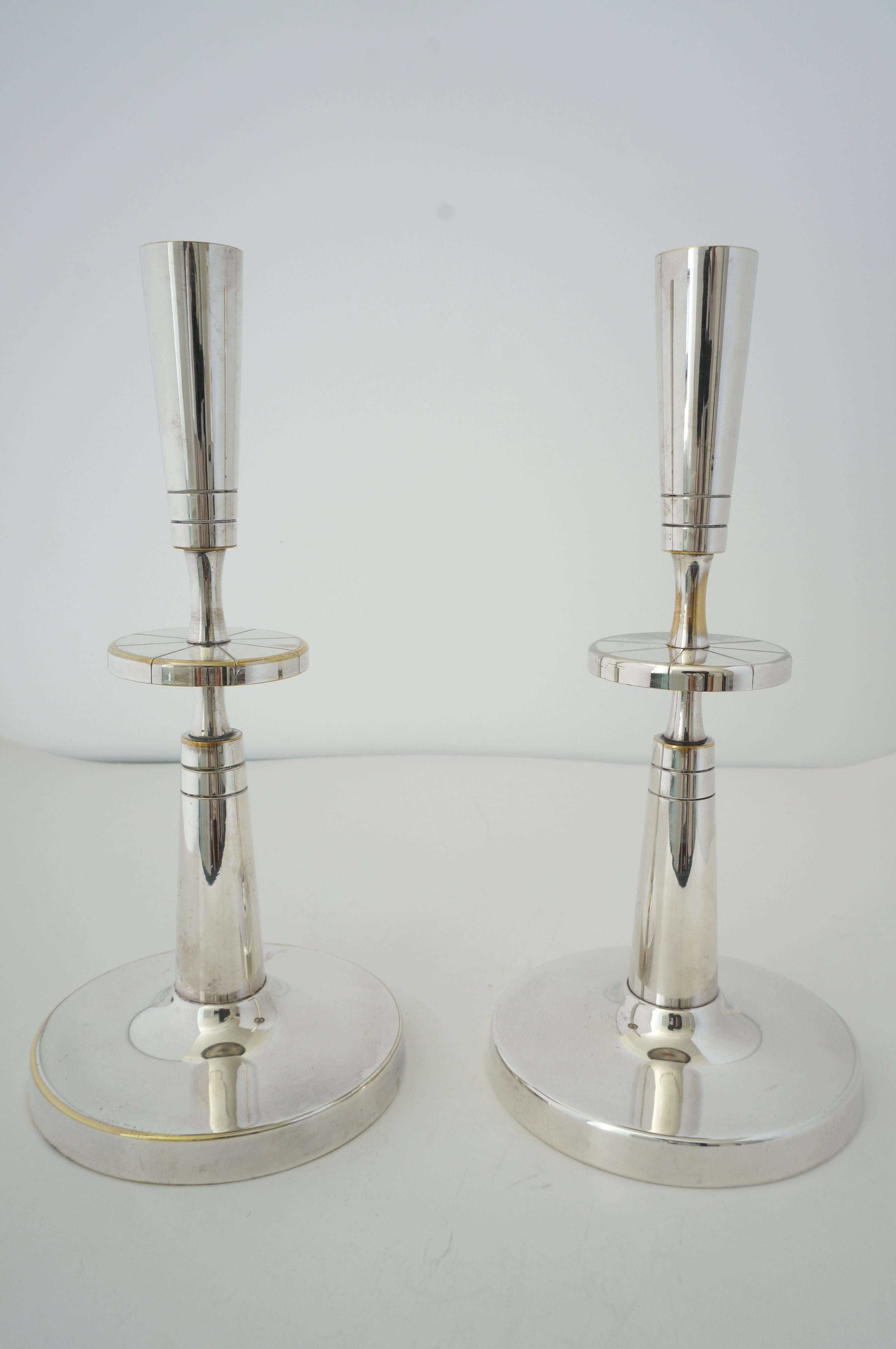 This stylish set of silverplate over brass candle sticks were designed by Tommi Parzinger for Mueck-Cary.

Note: Mueck-Cary Silverplate on the verso of the base.

Note: There is some loss of silver on various areas (see images).