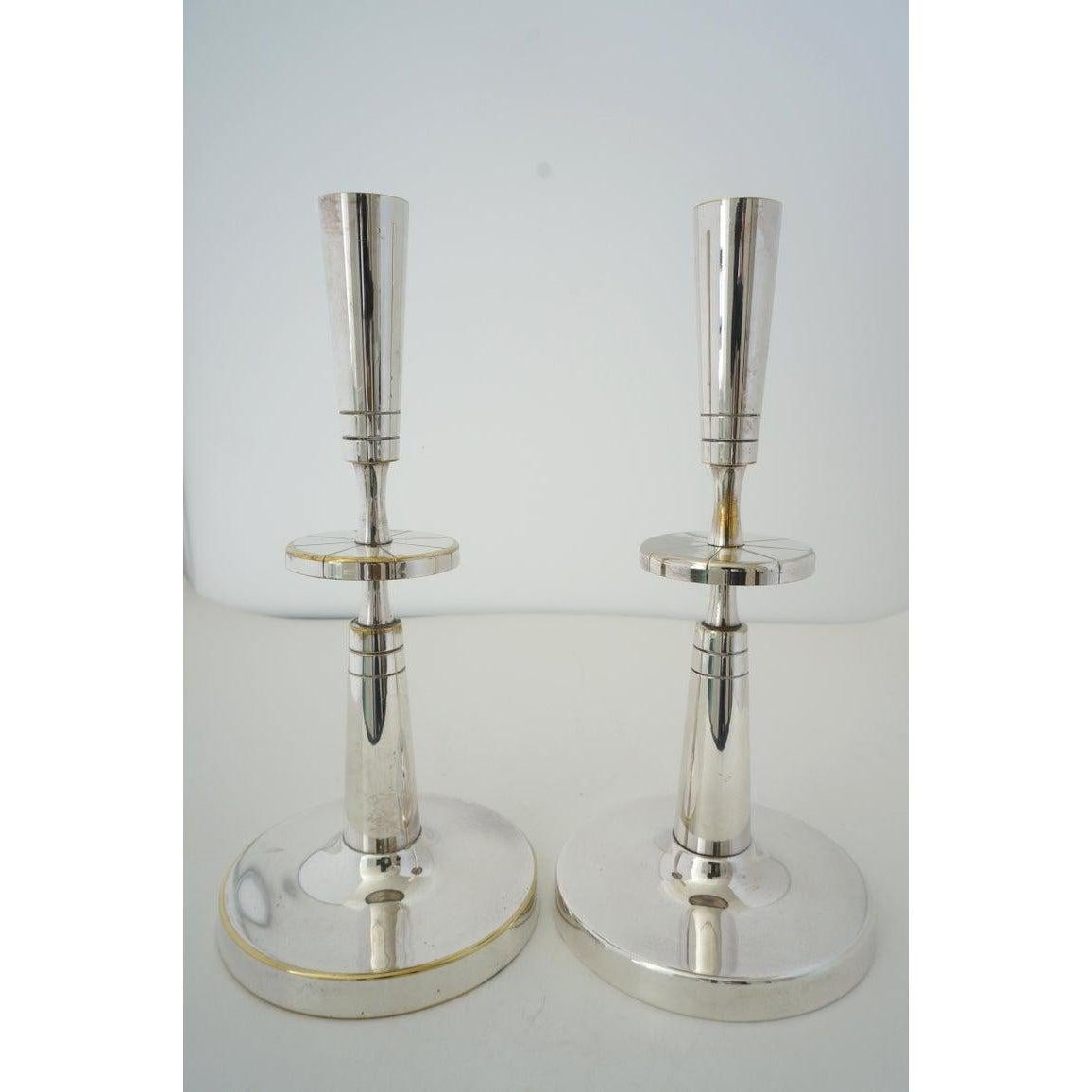 This stylish set of silverplate over brass candle sticks were designed by Tommi Parzinger for Mueck-Cary.

Note: Mueck-Cary silverplate on the verso of the base.

Note: There is some loss of silver on various areas (see images).