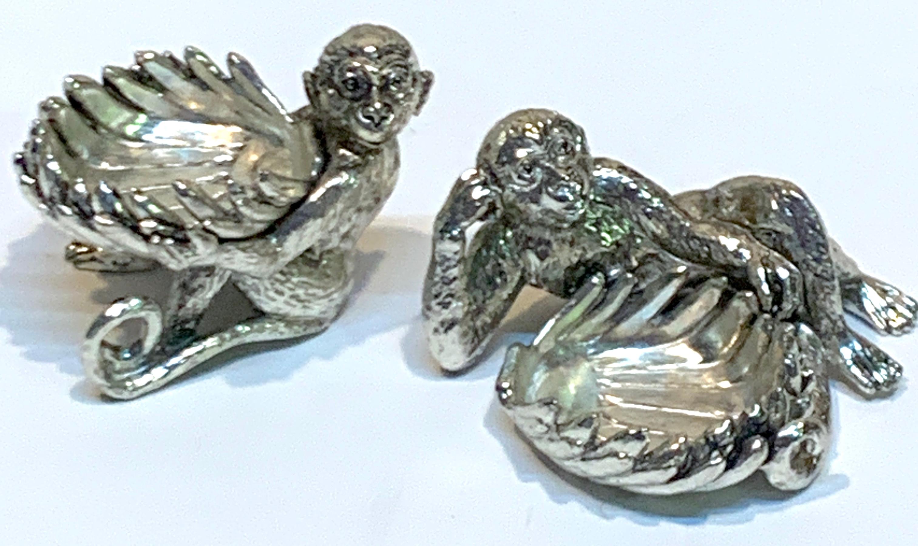 Pair of silver plated reclining monkey salts or nut dishes each one realistically cast and modeled holding banana bowls. Unmarked. 
Reclining monkey measures 3.75