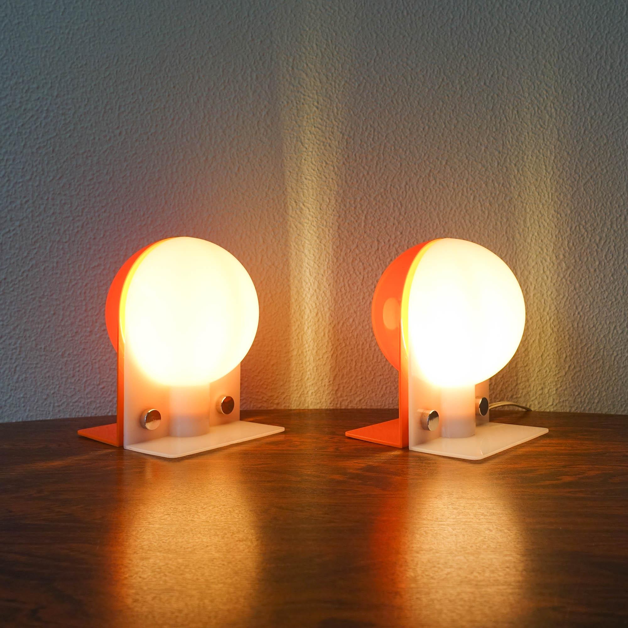 This pair of table lamps was designed by Sergio Brazzoli & Emmano Lampa for Harvey Guzzini, in Italy, during the 1970's. Each lamp features a white and orange acrylic half globes that are together throught two chrome fittings. These Harvey Guzzini