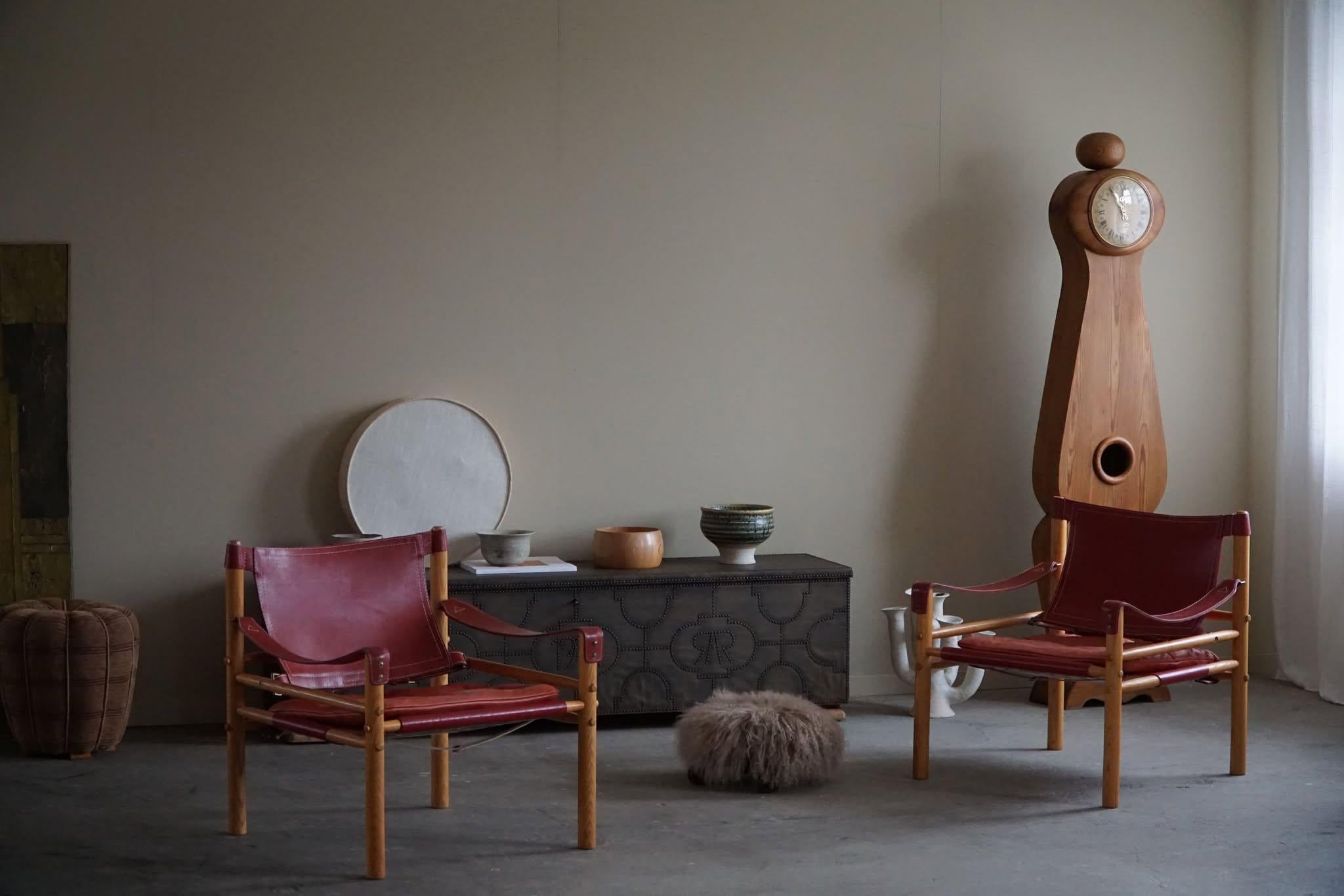 A beautiful pair of safari armchairs in a red leather and wooden ash frame. 
Designed by Arne Norell, produced by Arne Norell AB in Aneby, Sweden, in the 1960s.
This set is in a good vintage condition.

These appealing armchairs will fit into many
