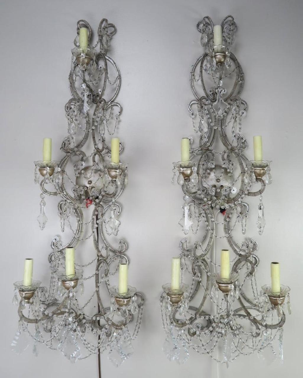 Coppia di appliques a sei luci in cristallo italiano con finitura argentata. Piccole perline decorano la cornice di queste applique. I cristalli a forma di pendolo e di mandorla sono presenti ovunque, insieme a ghirlande di perline di taglio