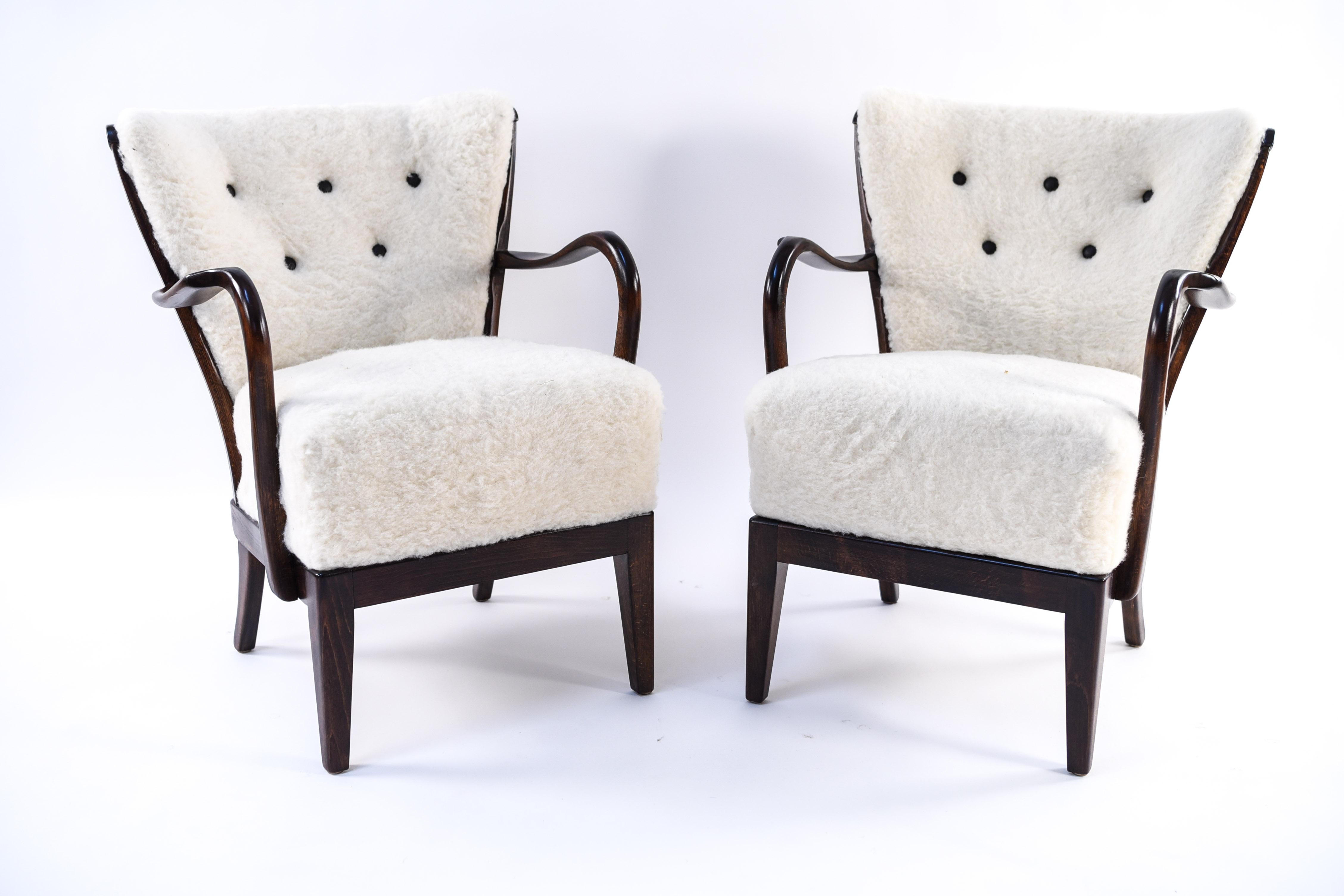 A pair of stunning model 177 lounge chairs by Slagelse. The beautiful lines of the chairs' design are accentuated by the lambs wool upholstery and button tufted back detail. A very attractive pair that epitomize the ingenuity of Danish midcentury