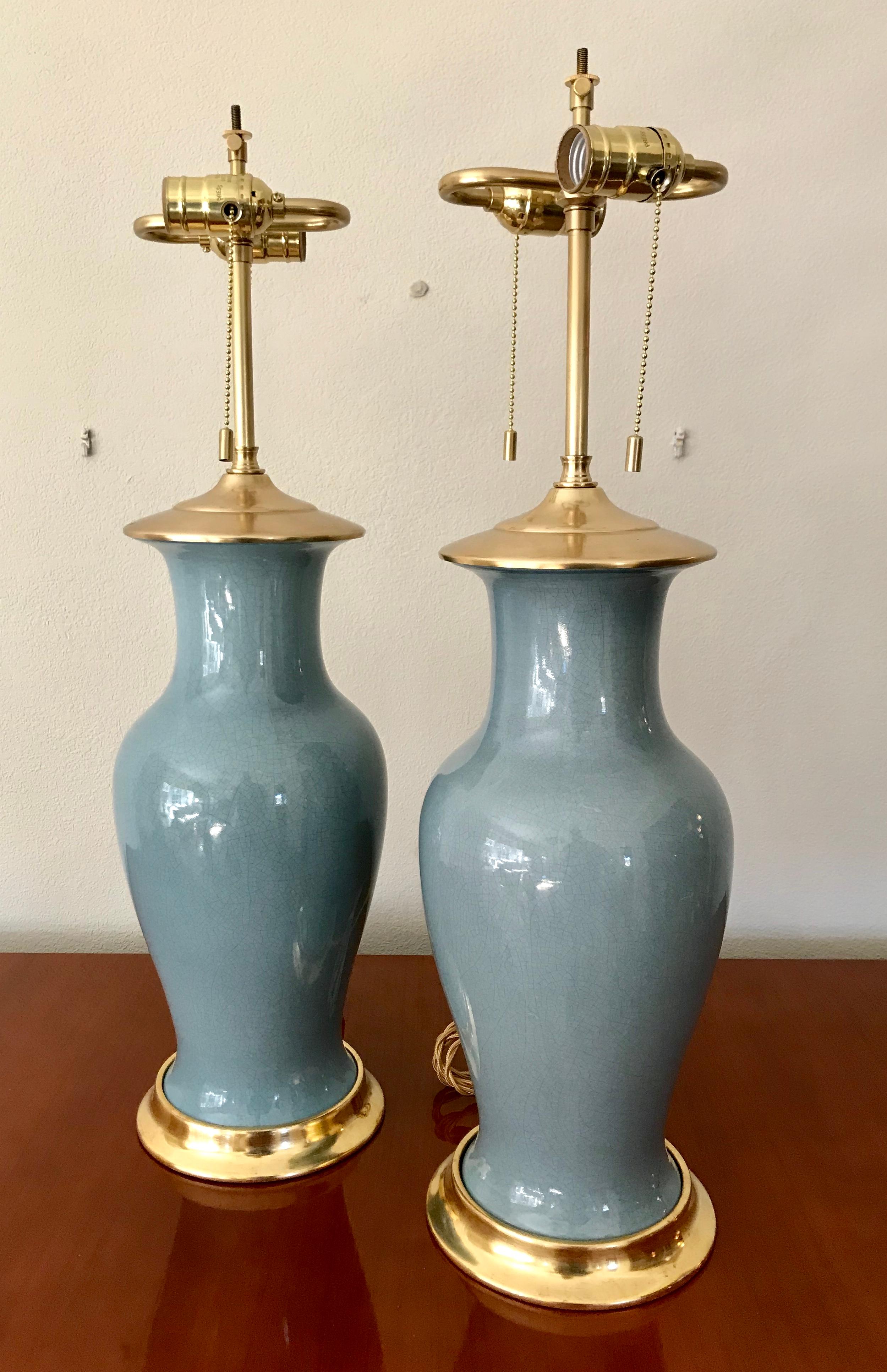 Pair of duck egg blue colored ceramic lamps on custom 23-karat water double gilt turned wood bases. Phoenix tail form ceramic bodies with a craquelure to overglaze. Overglaze has sheen, but is not glossy. Newly wired for US, each lamp uses 2 - A or