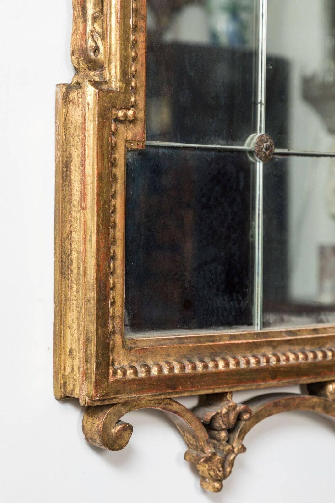 Two, carved, 22-karat gold gilded, circa 1880 frames featuring pierced serpentine crowns and aprons. Each inset with newer glass panels fastened by gilt metal, floral pins.