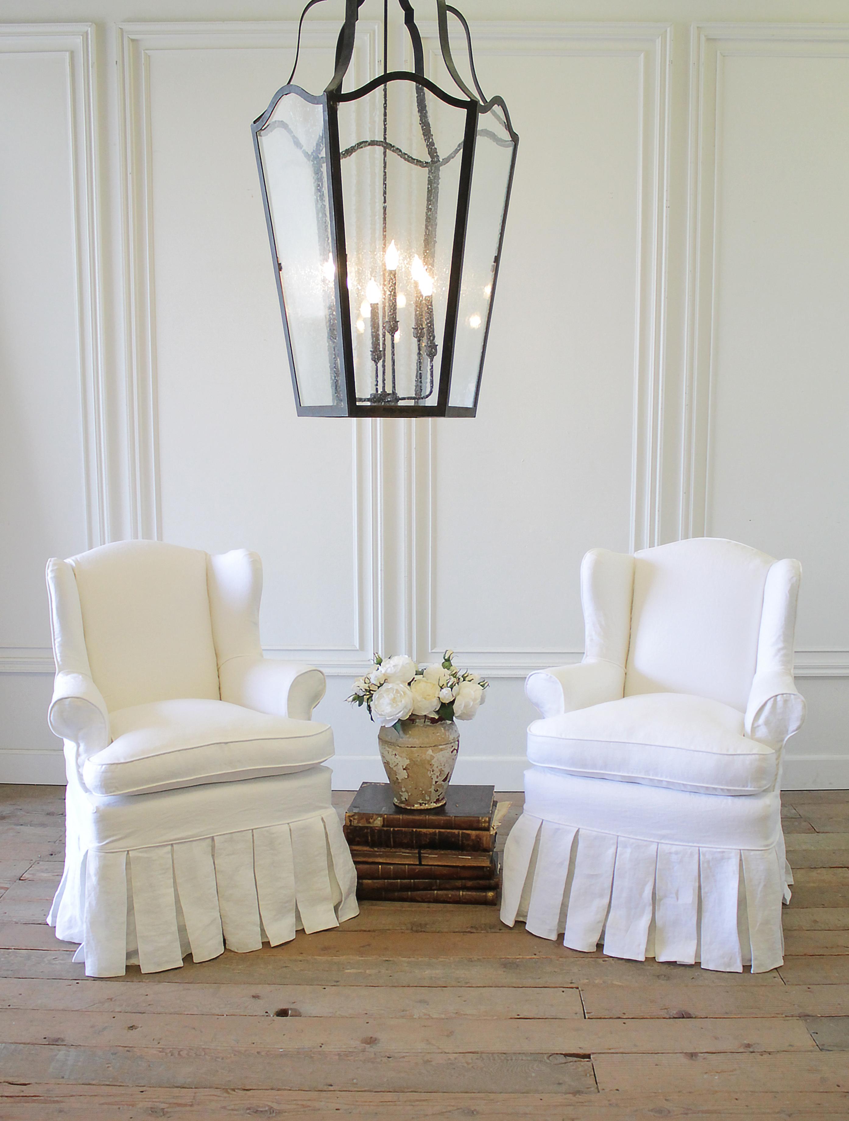 Pair of slip covered linen wing chairs with Ruffle Skirt
These vintage wing chairs are upholstered in white canvas, with decorative walnut legs. We added new down seats which are very comfortable. A brand new custom made 100% Belgian linen slip
