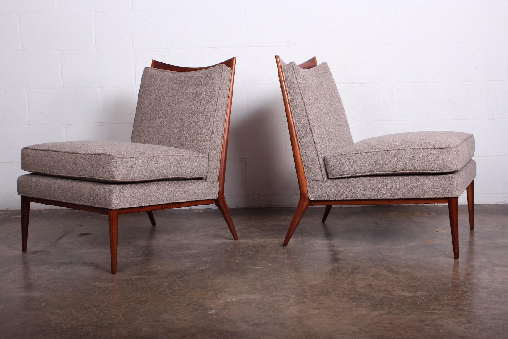 A pair of slipper chairs with walnut frames. Designed by Paul McCobb.