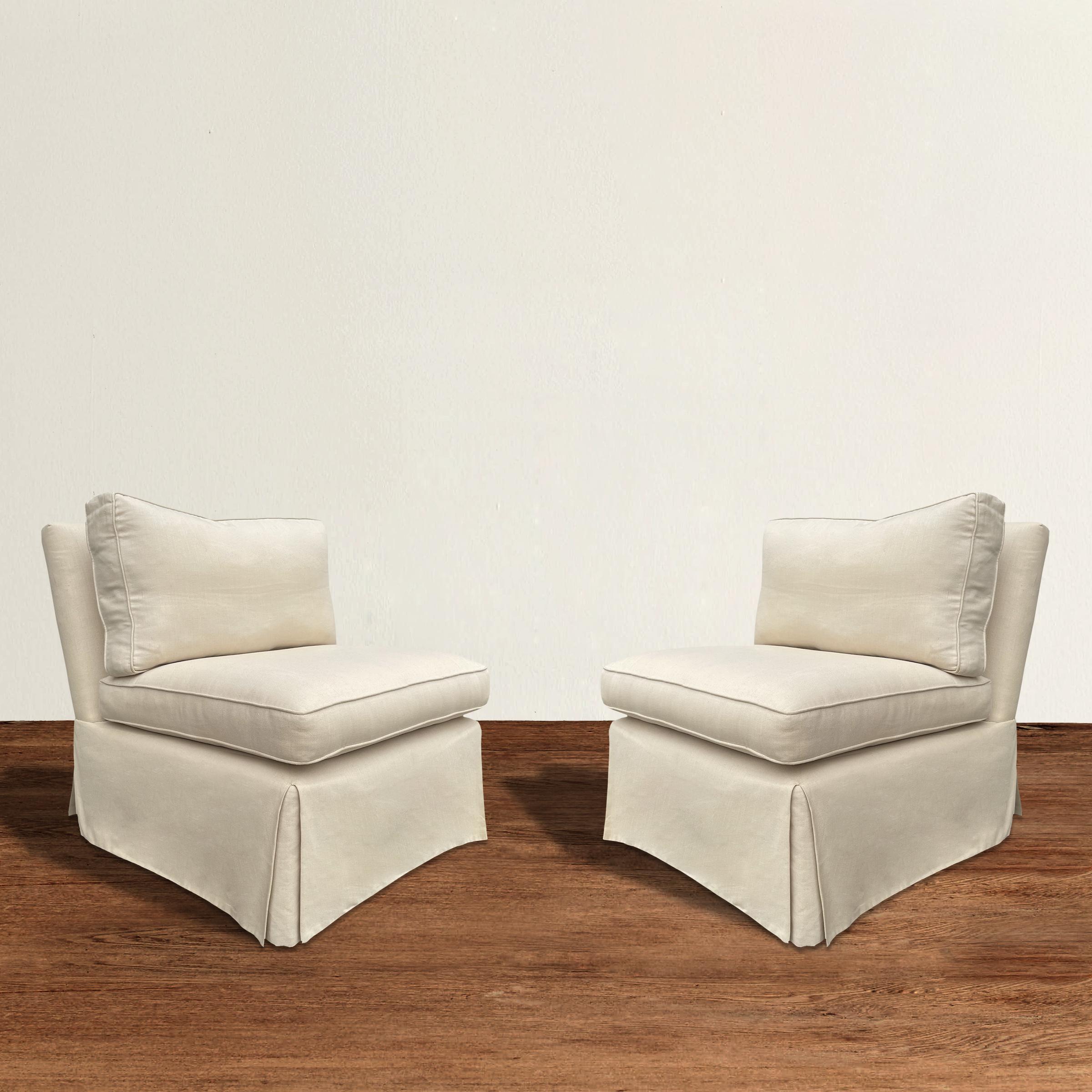 A pair of custom made slipper chairs upholstered in linen, with down filled back cushions, down-wrapped-foam seat cushions, and waterfall skirts.