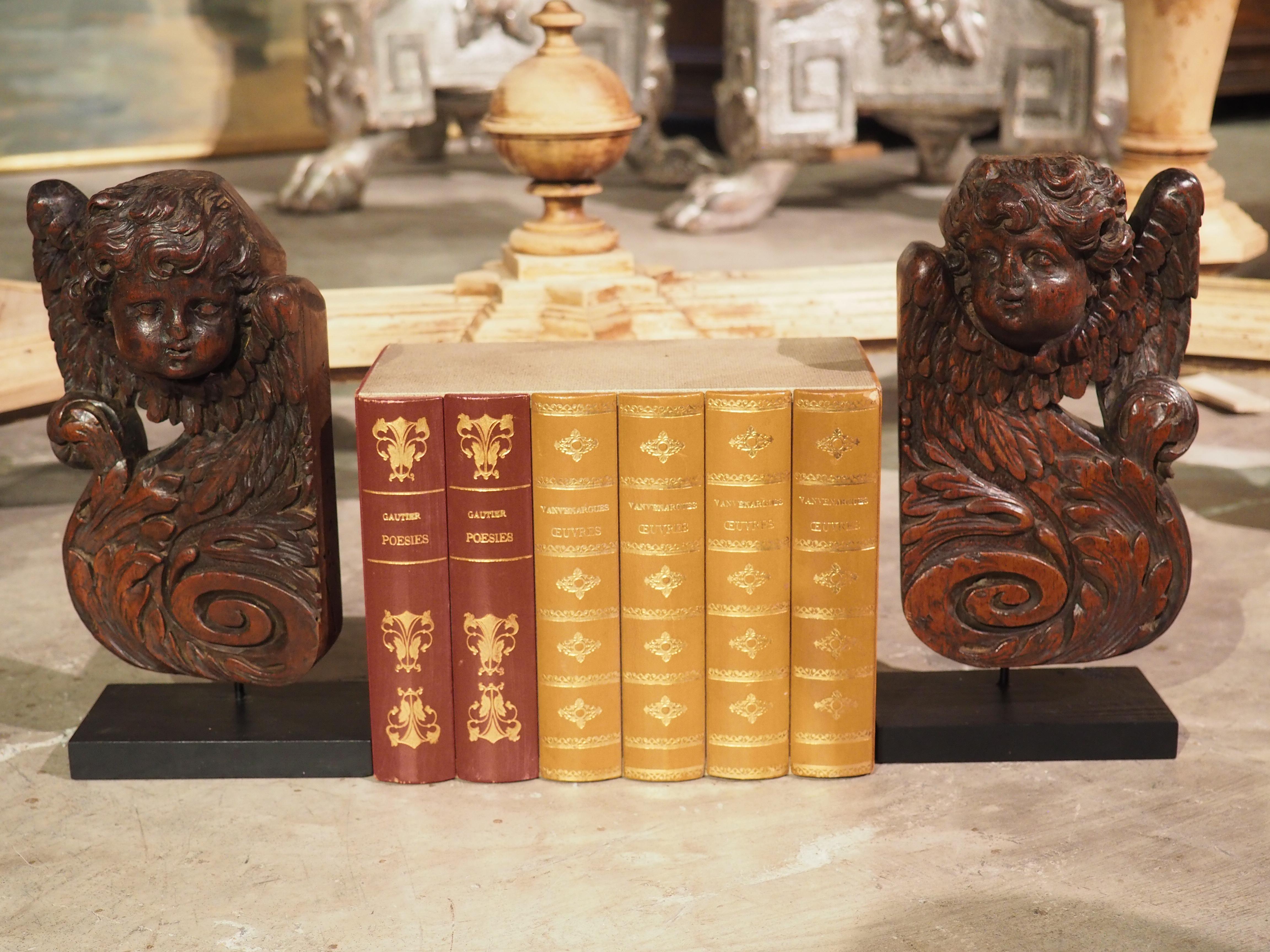 This pair of small angel sculptures were hand carved in walnut in France during the 1600s. The angels are mirror images of each other, although there are variations to the carvings, most noticeably the faces. Both sculptures depict an angel head