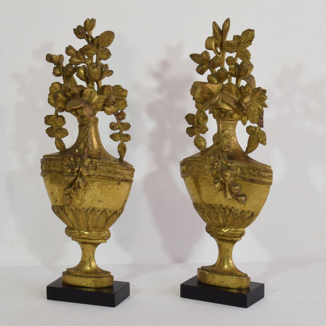 Nice couple of two giltwood neoclassical vase ornaments,
France, circa 1780-1850. Weathered, small losses and old repairs. Measurement here below includes the wooden base.