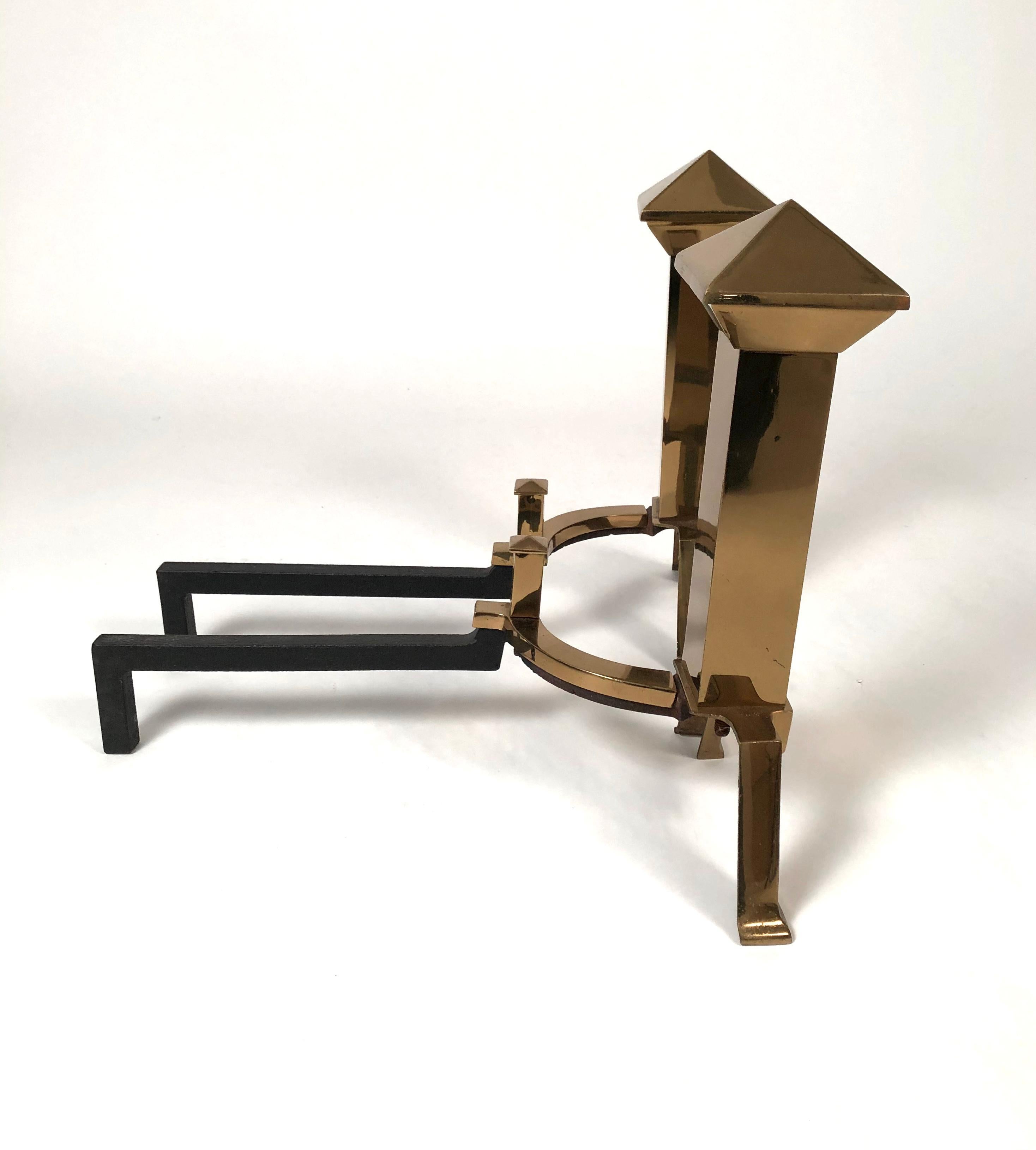 A pair of small Aesthetic Movement period brass andirons, inspired by Japanese design, the pyramid shaped tops over square section shafts with angled feet and conforming log stops. Ideal for a small fireplace, these andirons have an uncommon form