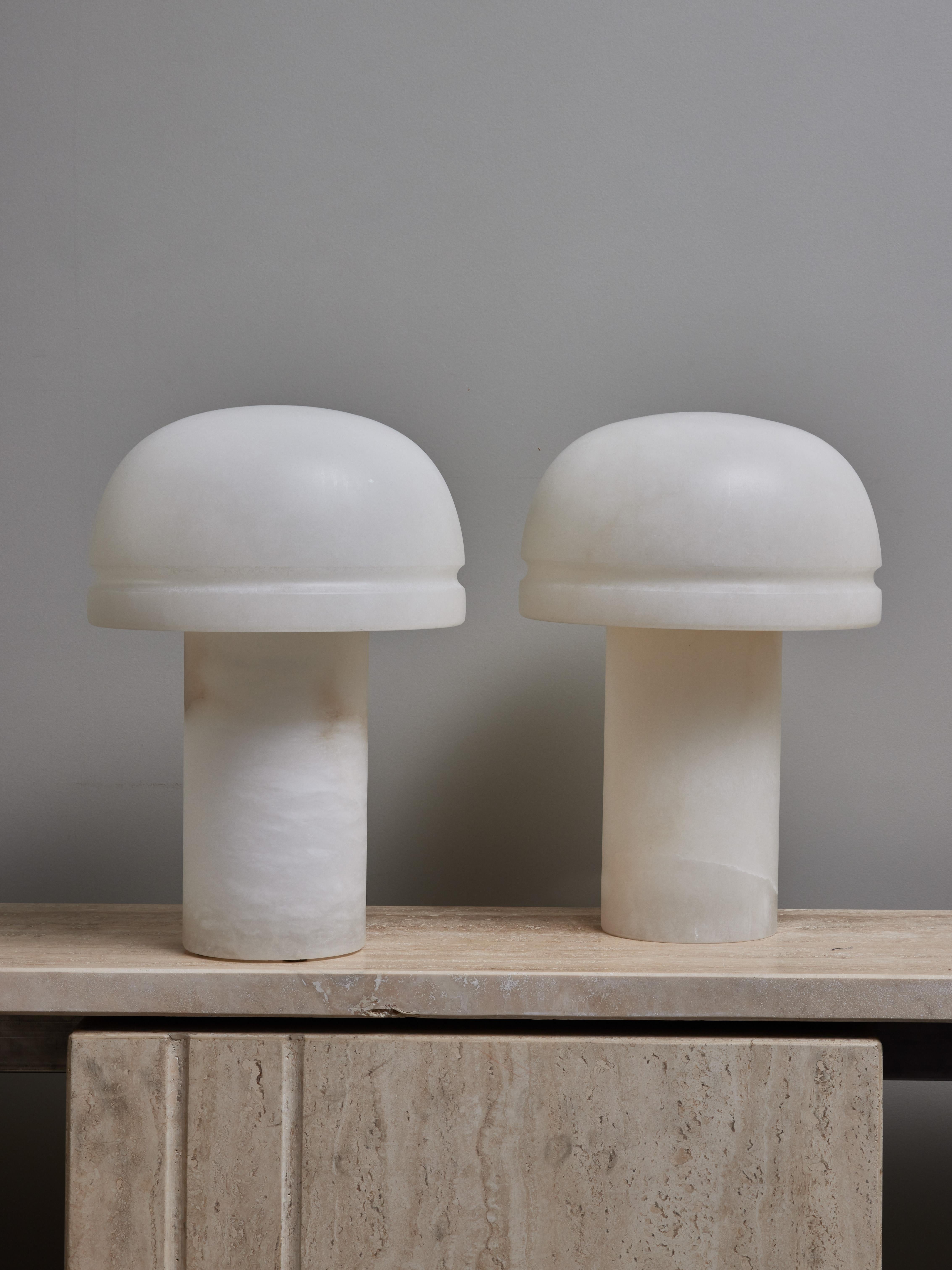 Pair of small table lamps made of two pieces of alabaster, a cylindrical base and a curved shade.