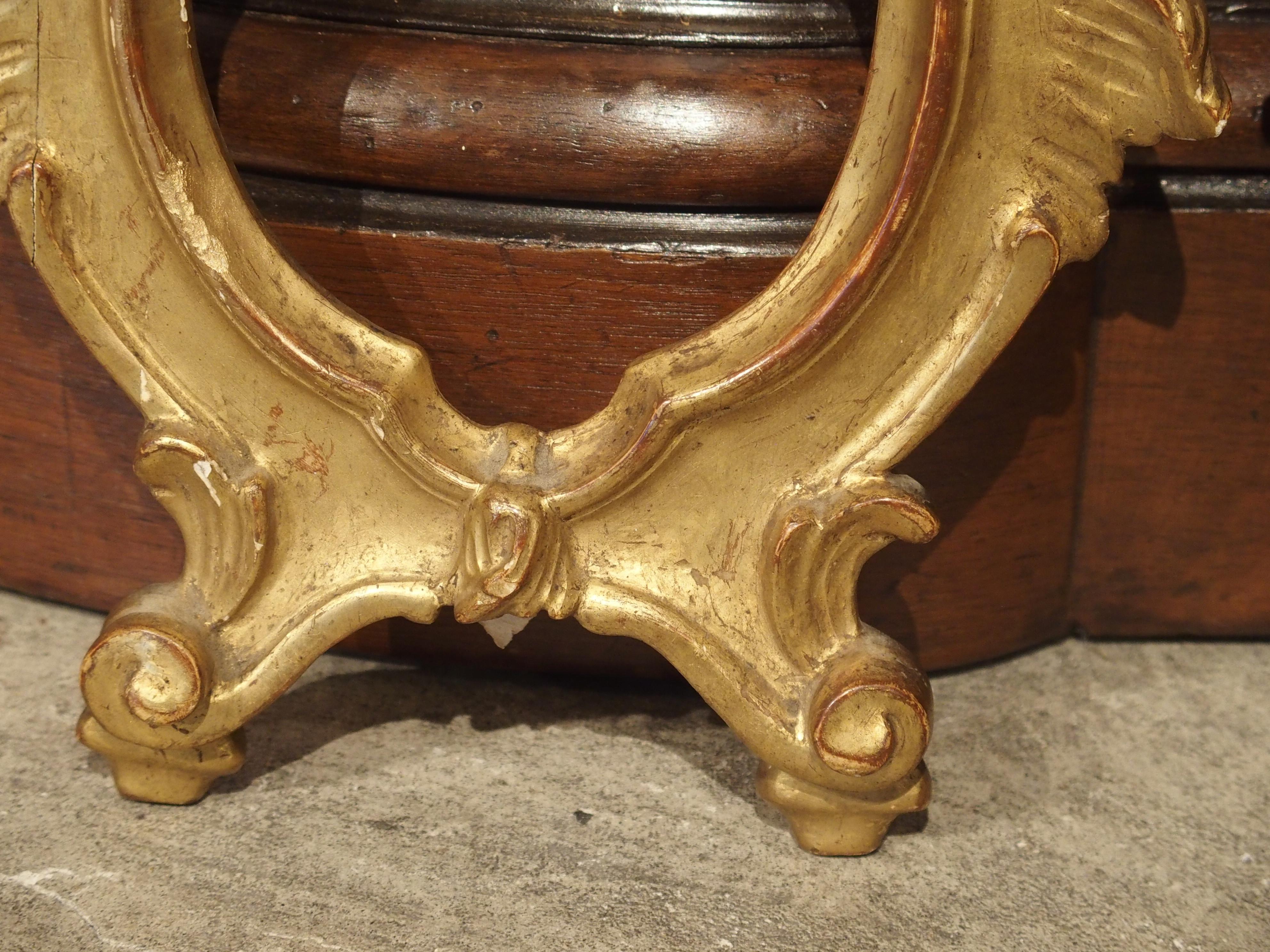 This pair of Louis XV Style Italian, giltwood frames have the asymmetrical acanthus leaf, typical of the Louis XV design. Separate leaves line both sides about half the way down the sides of the frame. Two feet are beneath two scrolls with leaves.