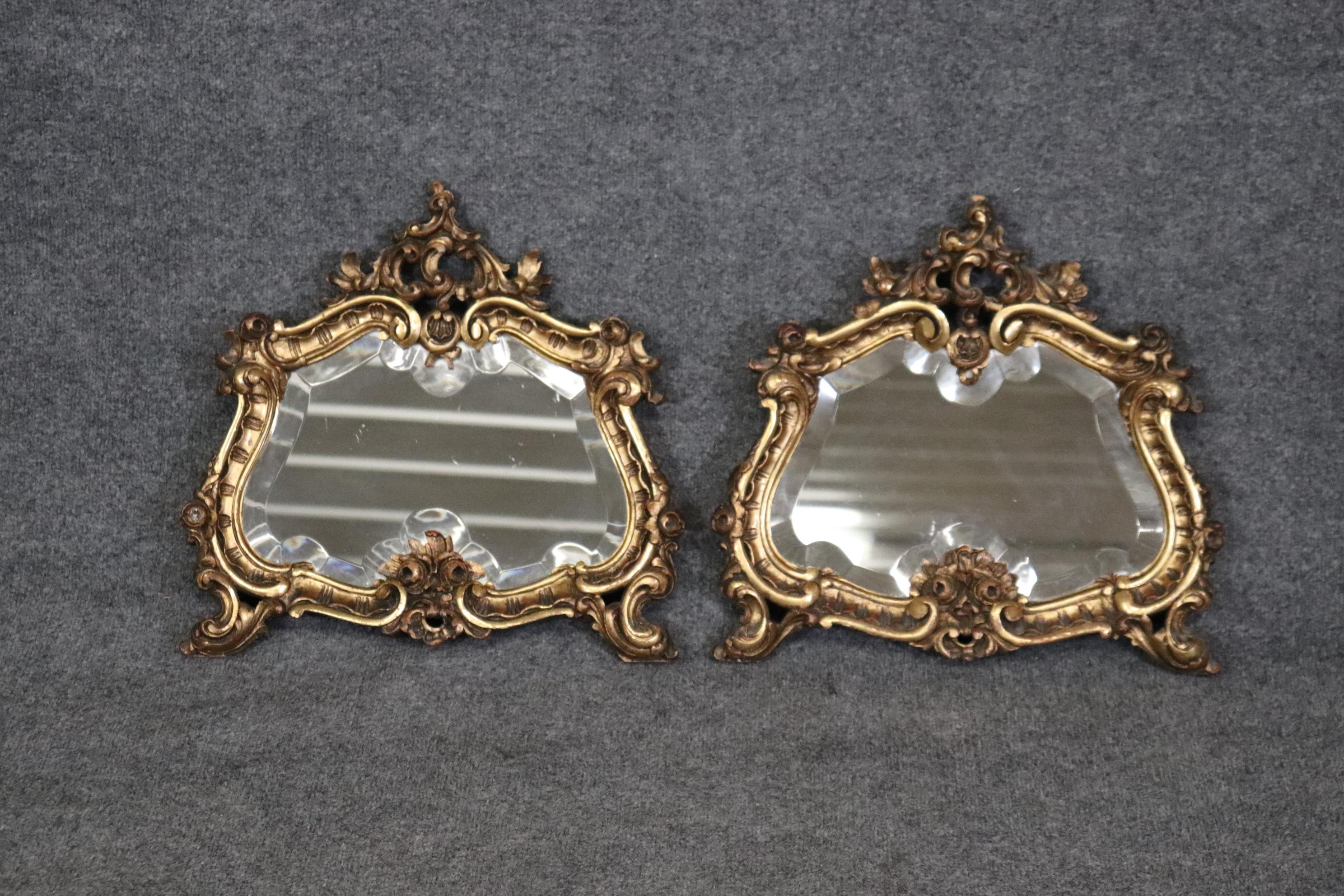 This is a gorgeous pair of small beveled glass gilded wooden Rococo mirror. The pair of mirrors is in good condition with minor signs of age and use such as age cracks or small repairs. They measure 18 inches wide x 17.25 tall x 2.25 and date to the