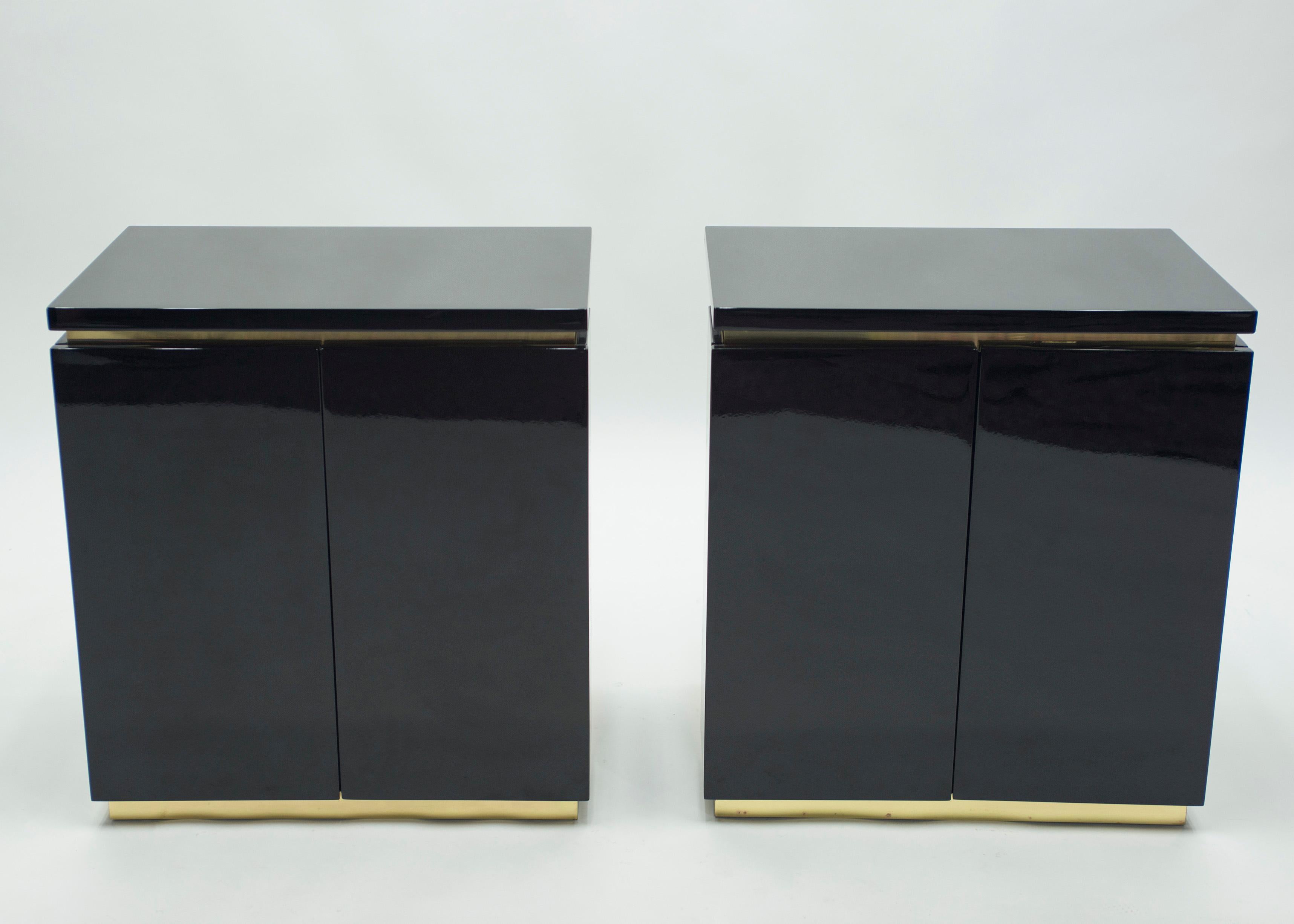 Glossy black lacquer, paired with bright brass accents, feels crisp and luxe on this pair of small cabinets. Their boxy, simple style is typical of both the 1970s and designer Jean Claude Mahey for Maison Romeo design. Whether used as two small